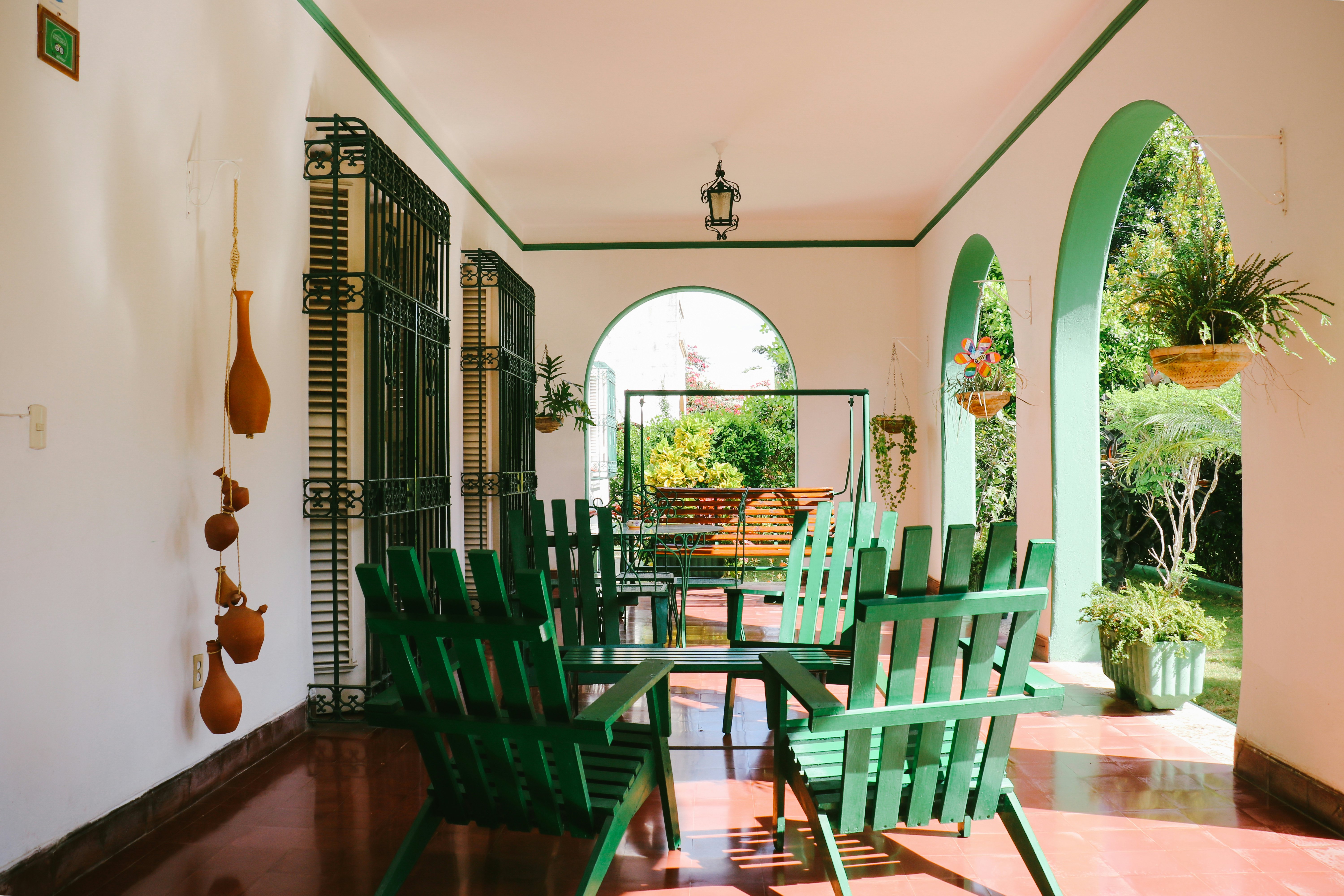 Chairs and a table on a veranda with arches in a city in the tropics.