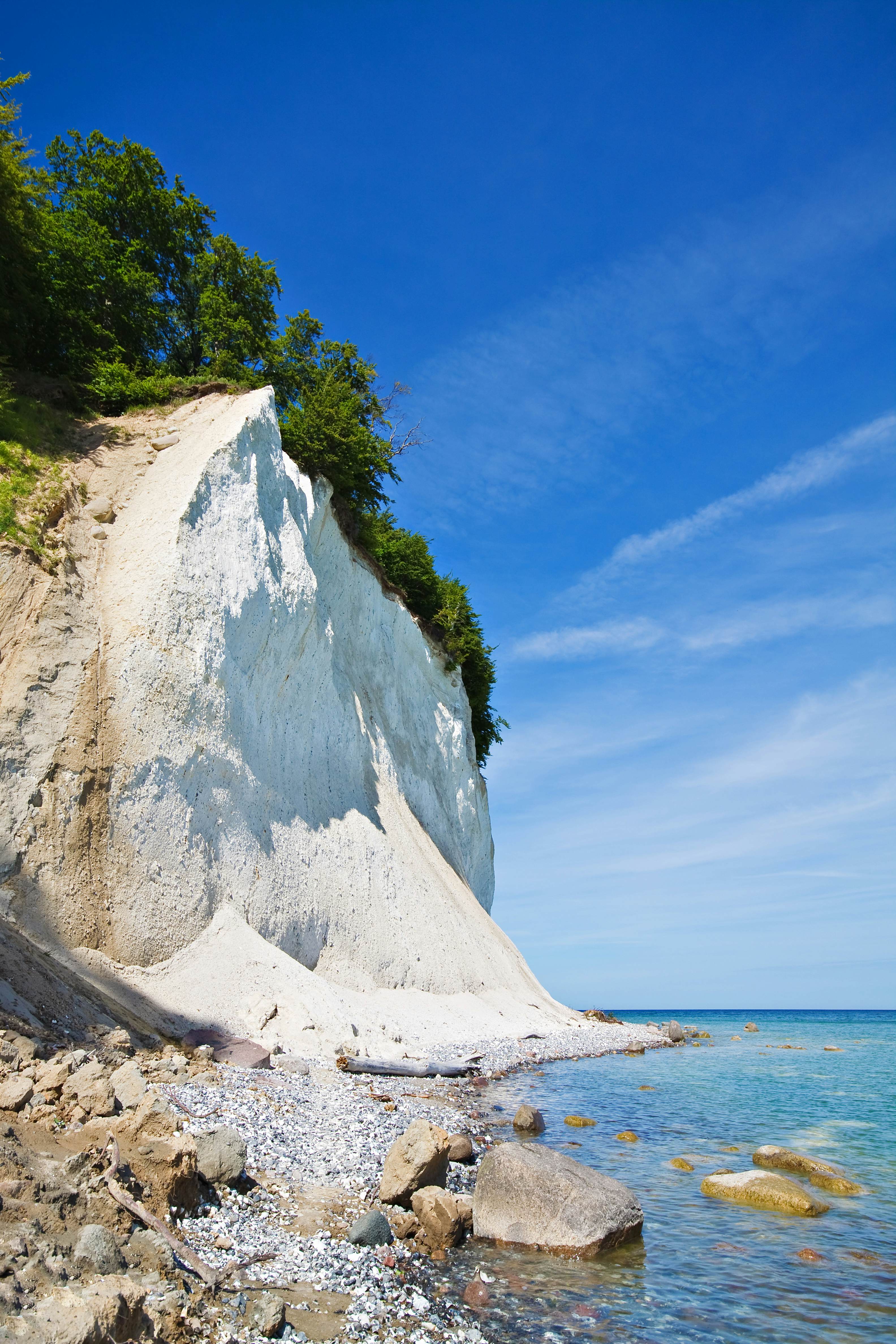 A white, chalky cliff overlooking the sea on a sunny day.