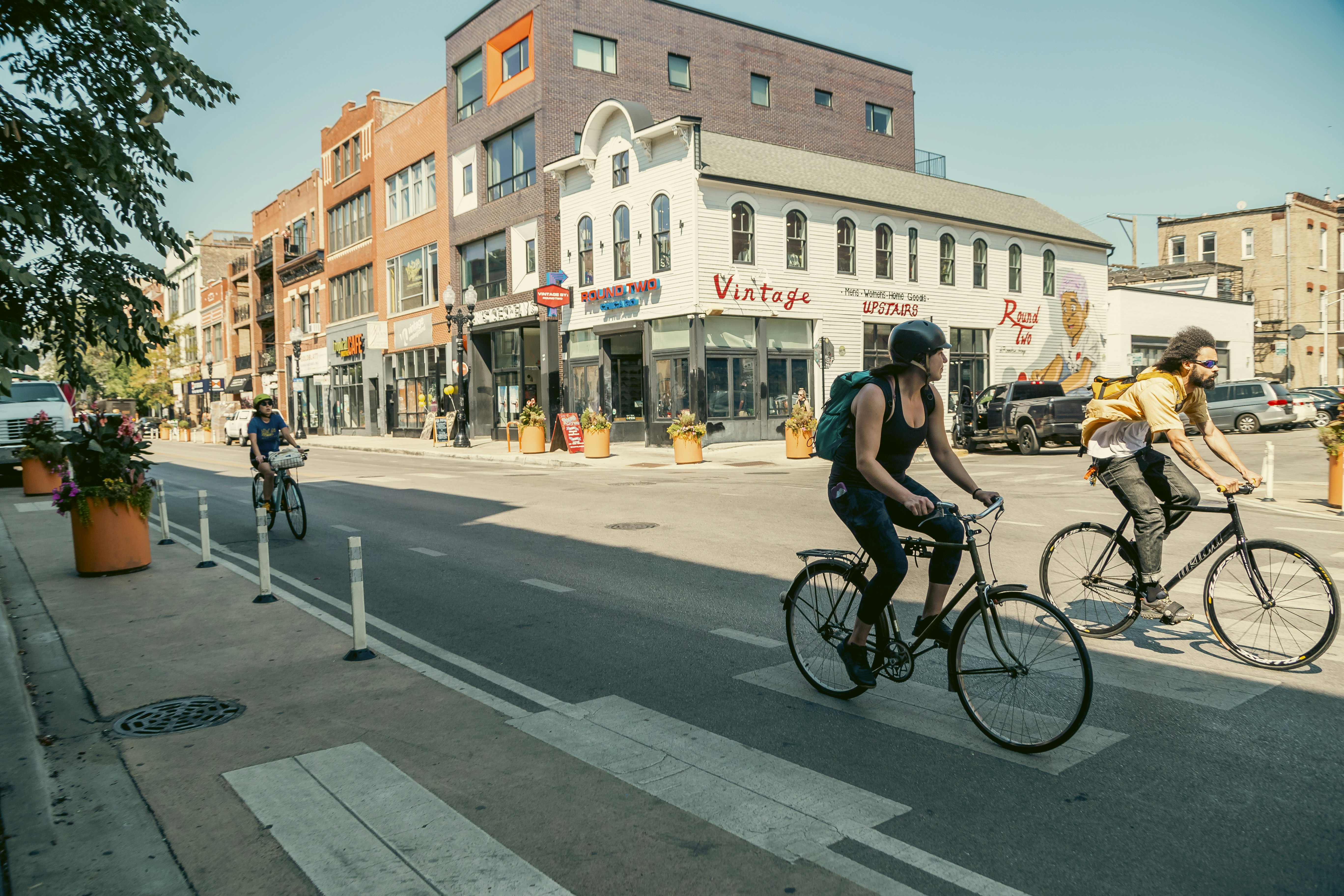 Cyclists on a quiet Chicago street that's lined with restaurants and vintage stores.