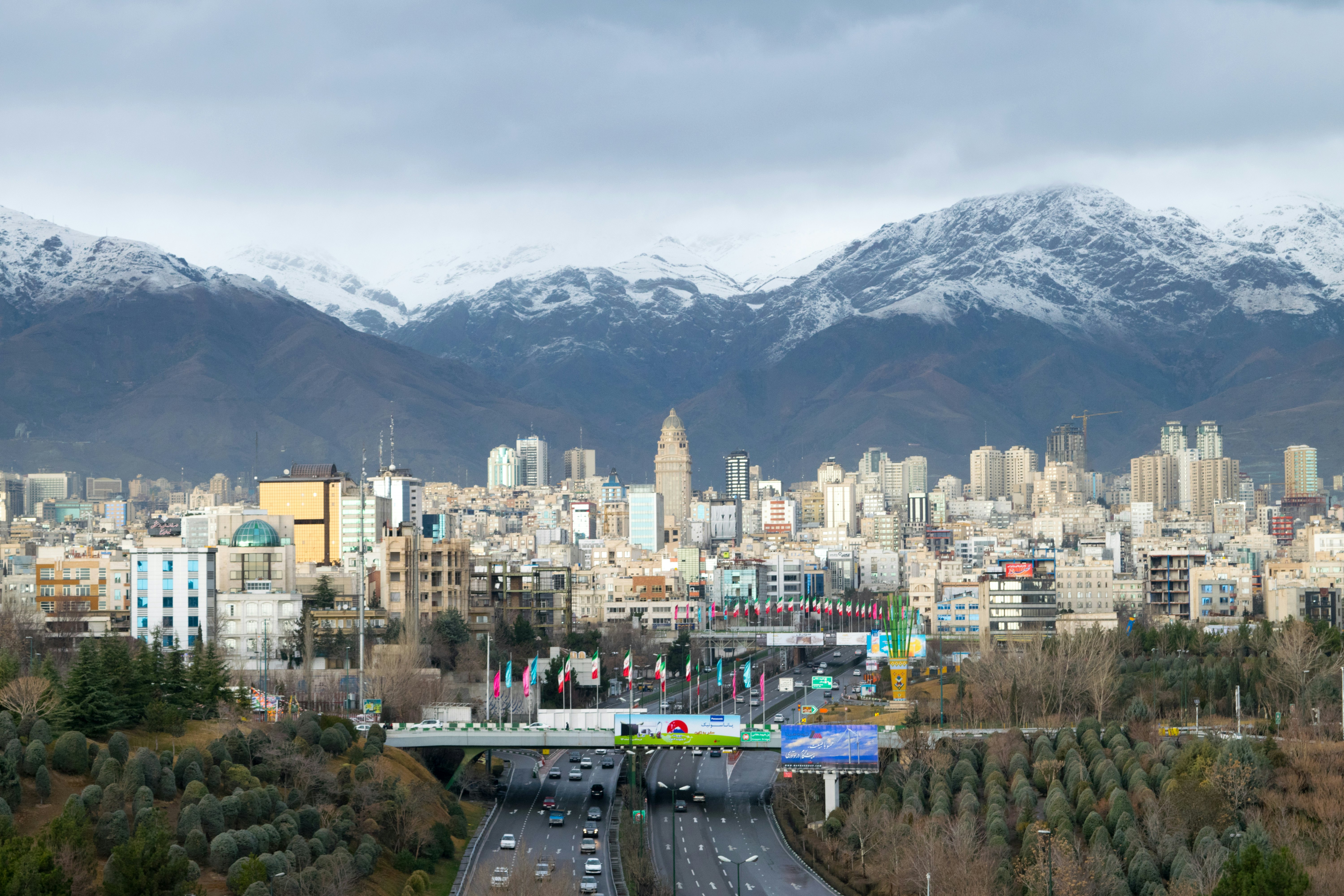 A city skyline at the foot of a snow-capped mountain range.
