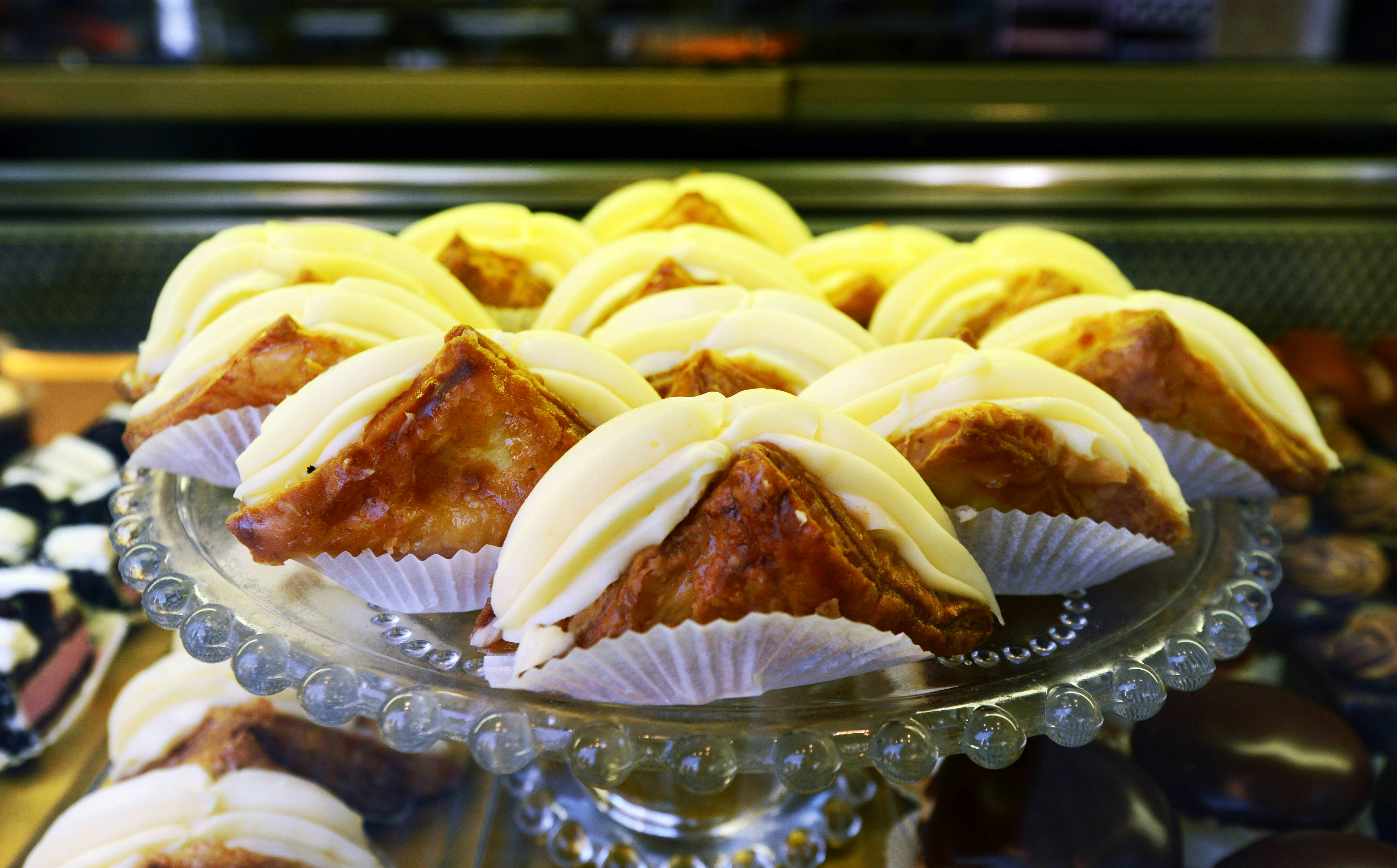 A round glass platter of triangular pastries filled with cream.