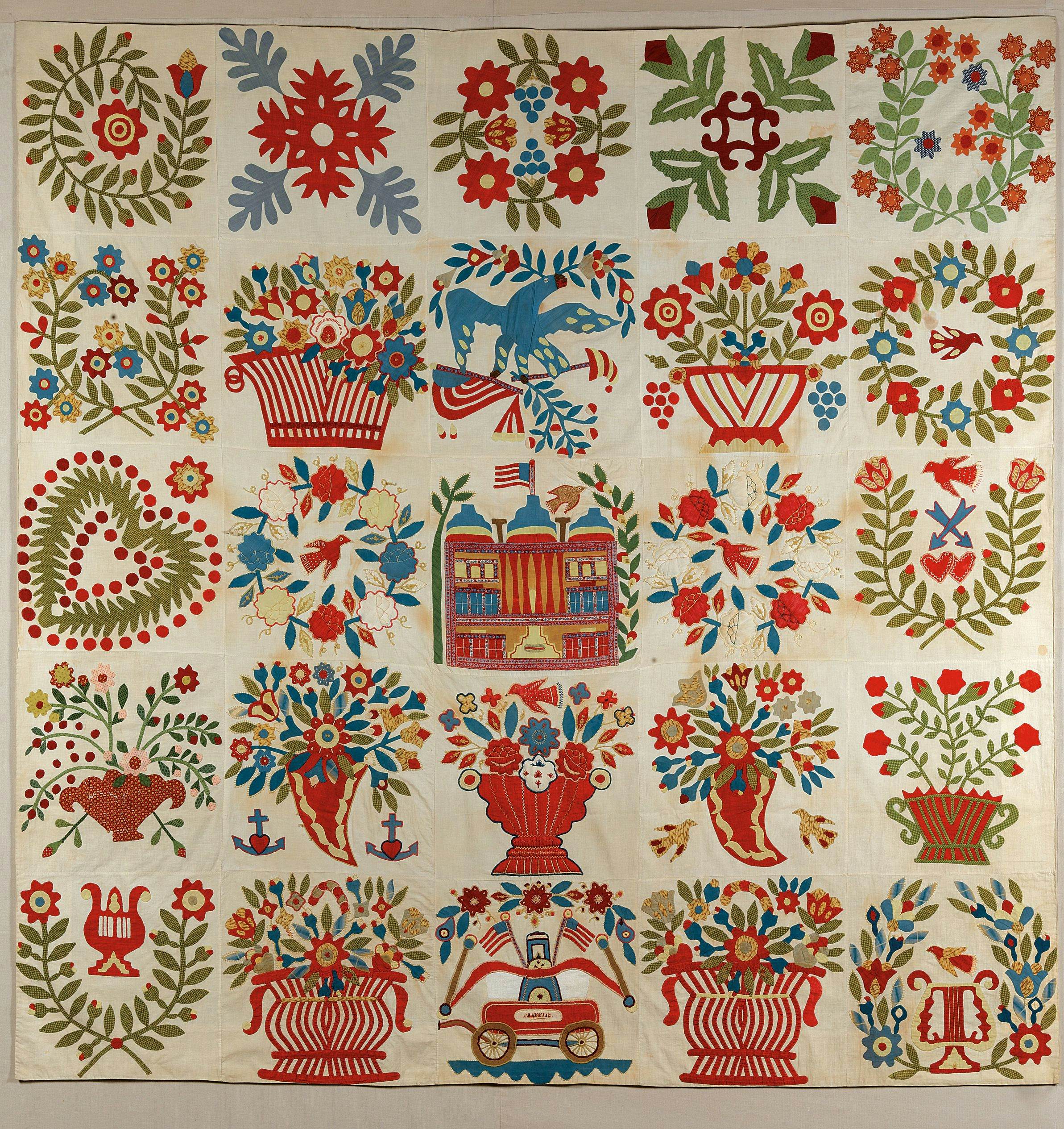A quilt whose panels show various floral and heart-inspired motifs.