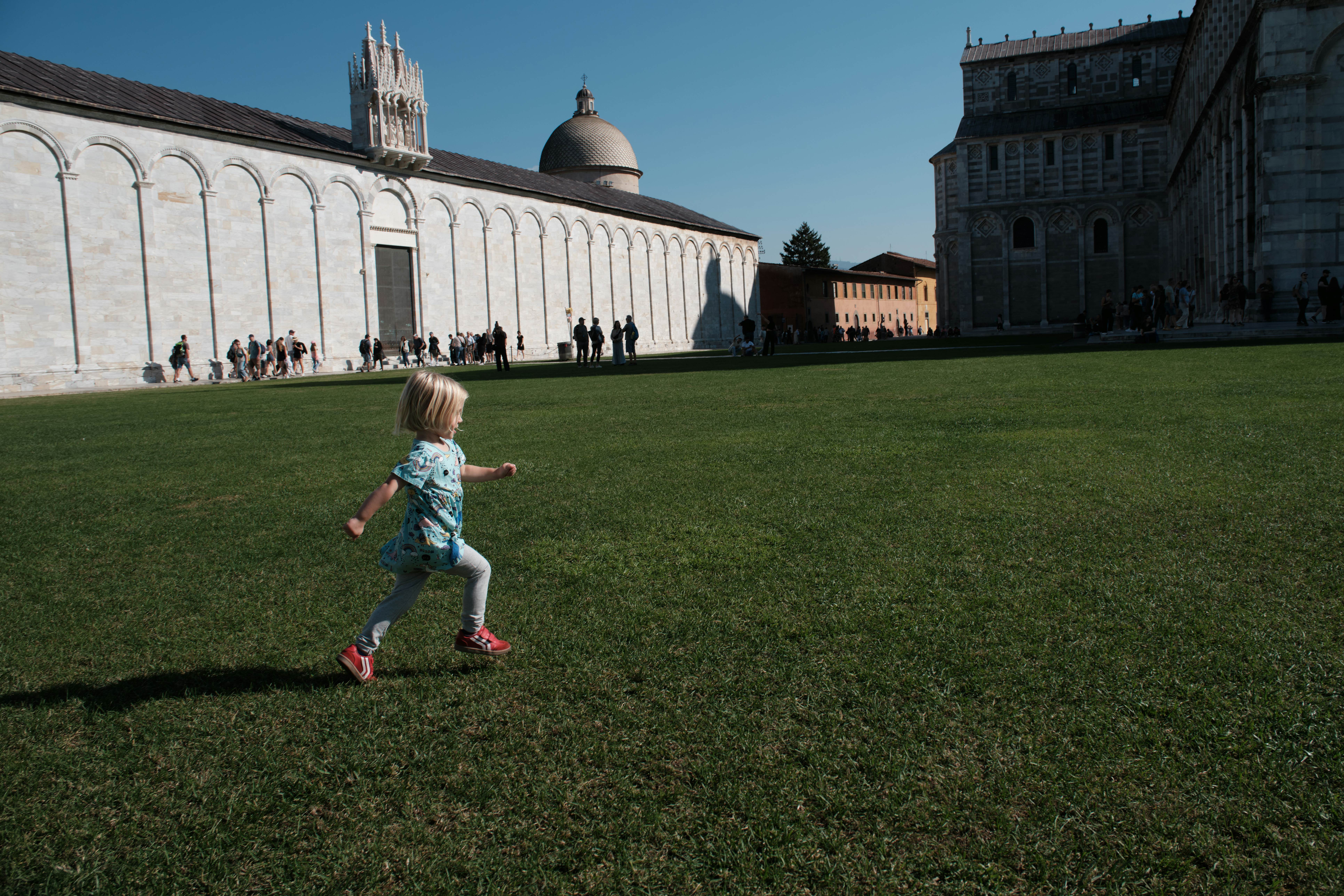 Maggie running across the lawn of Piazza del Duomo, Pisa