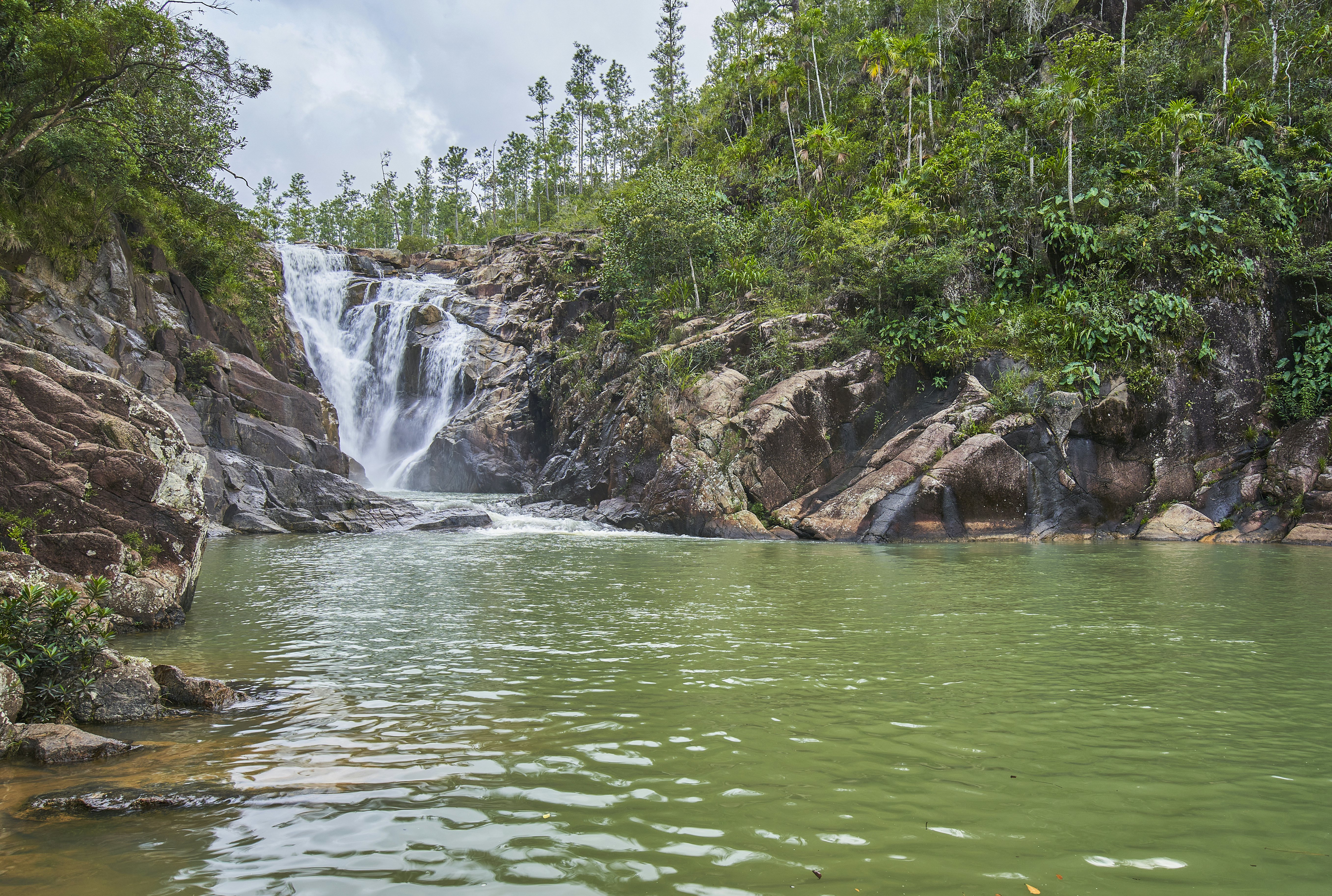 A waterfall plunges into a pool surrounded by big boulders.