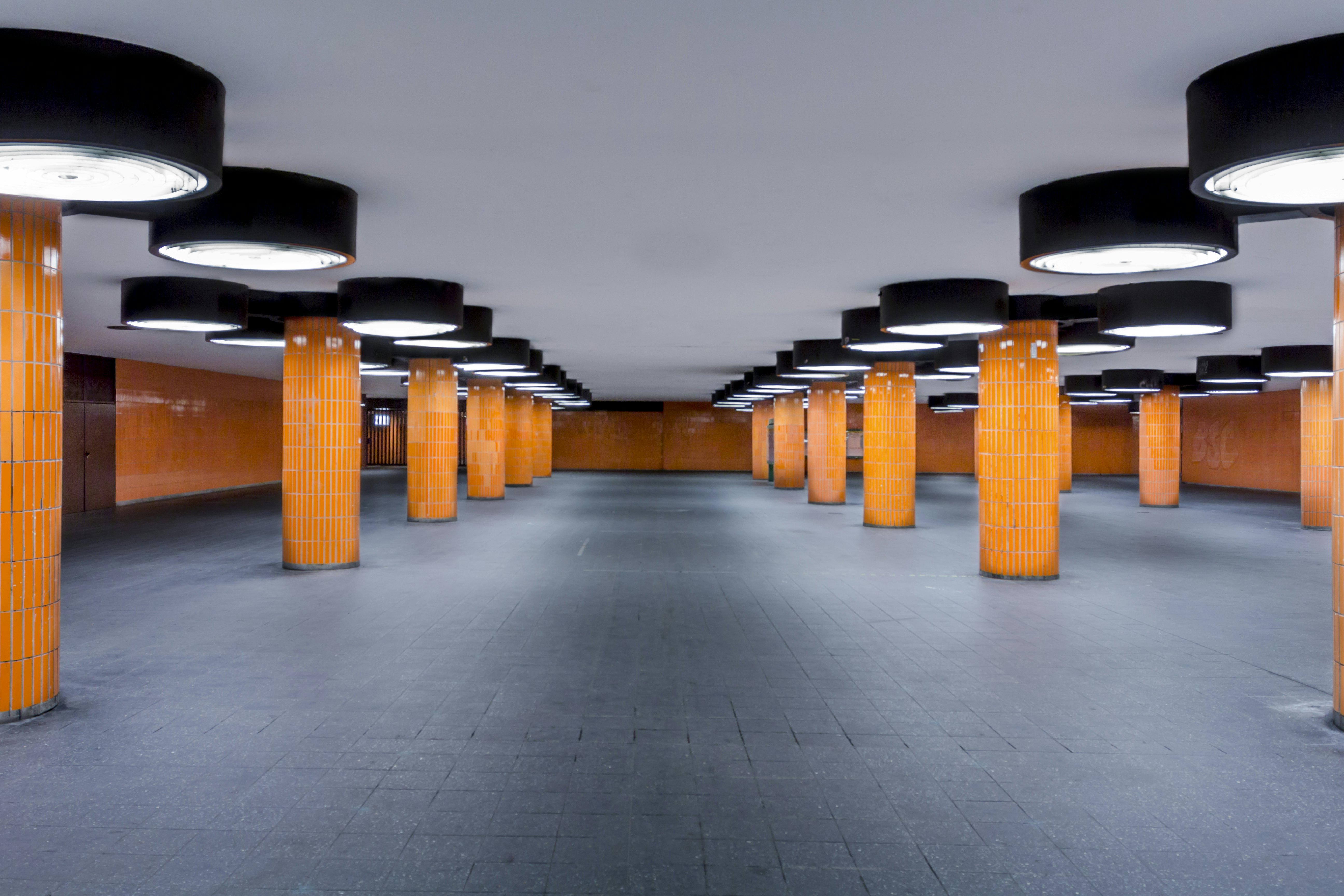 An empty underground concourse with orange tiled columns.