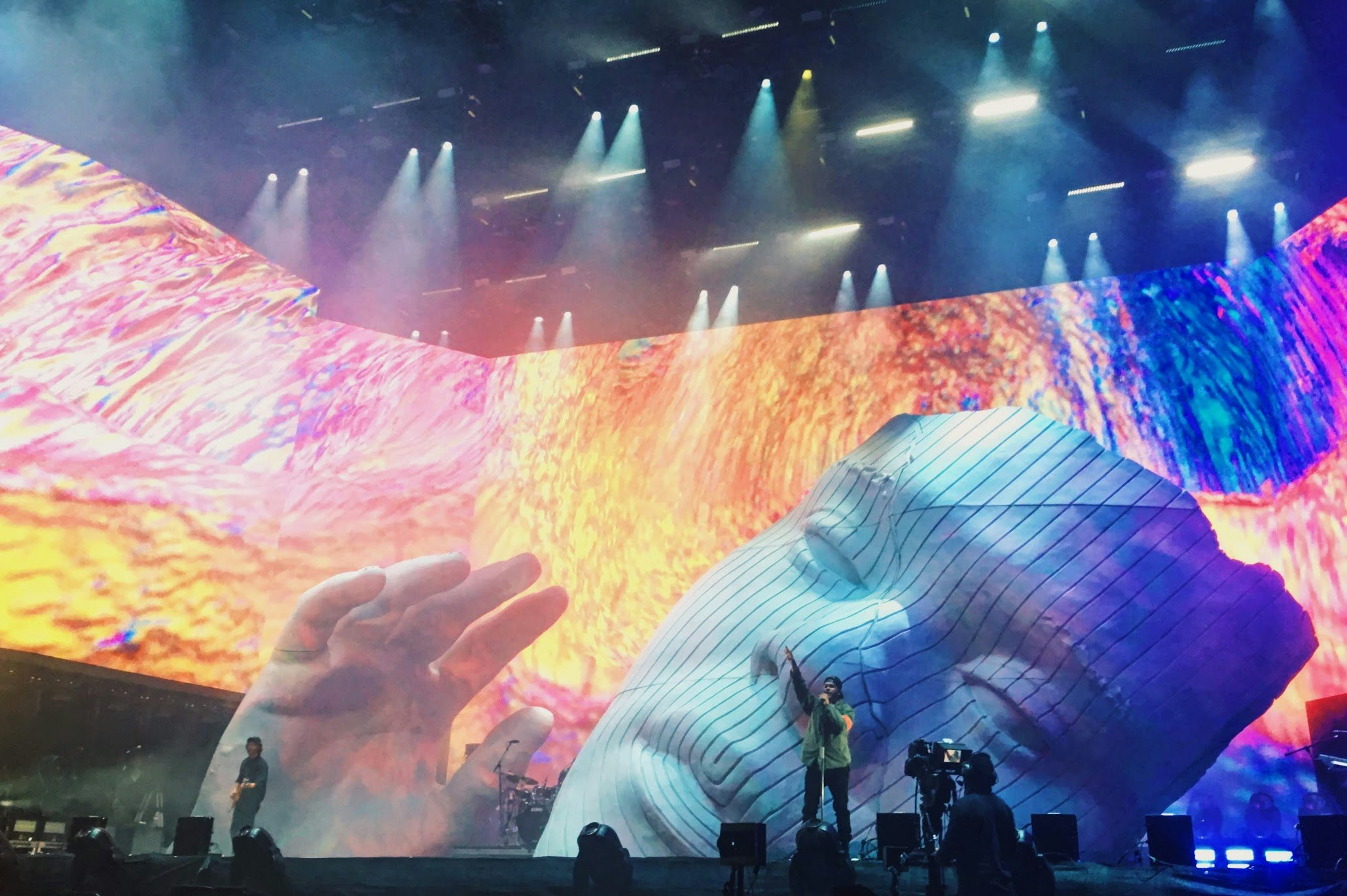 A man performing in front of a large colorful stage.