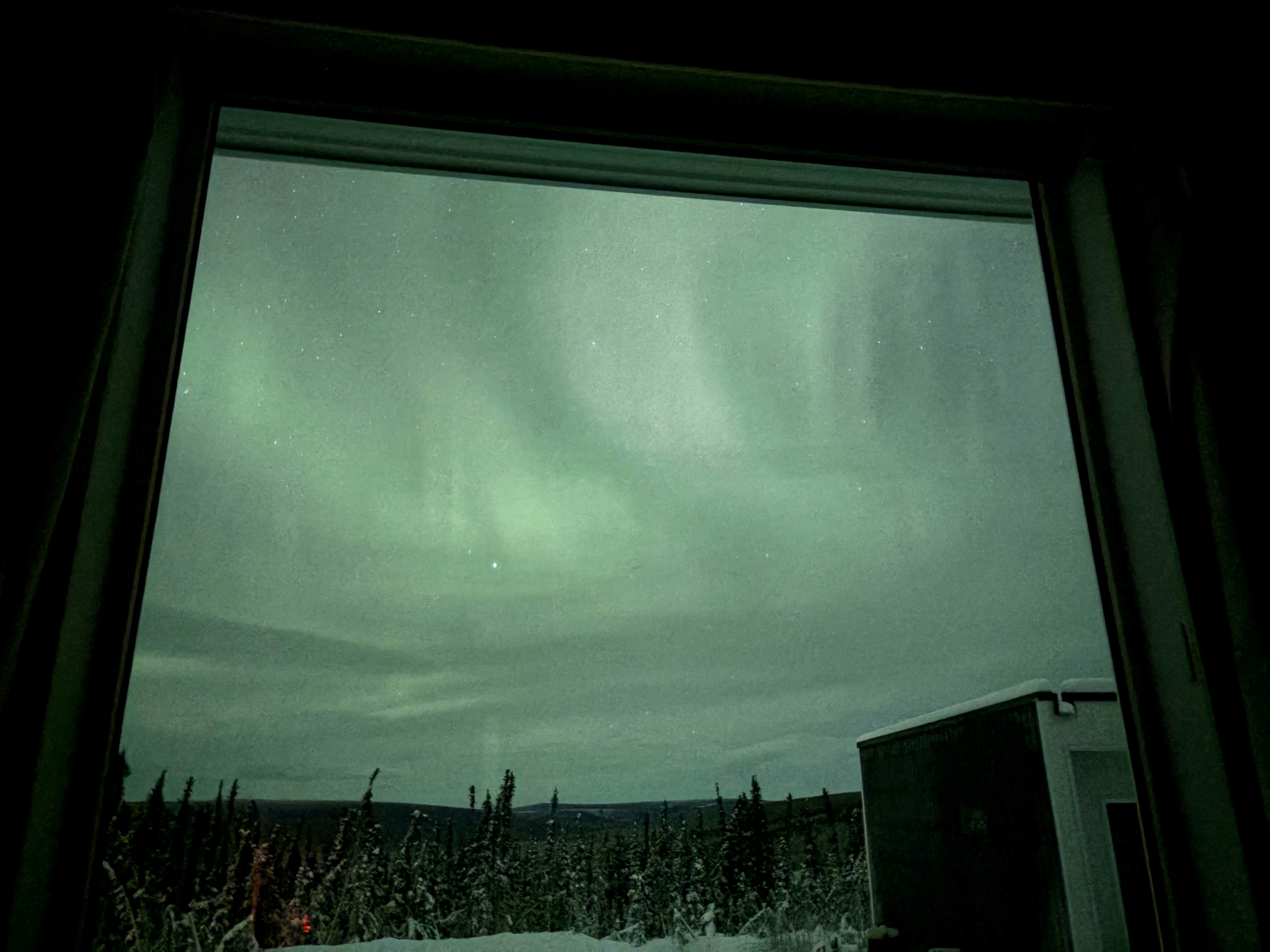 Hazy wisps in a greenish sky through a window in Fairbanks, Alaska.