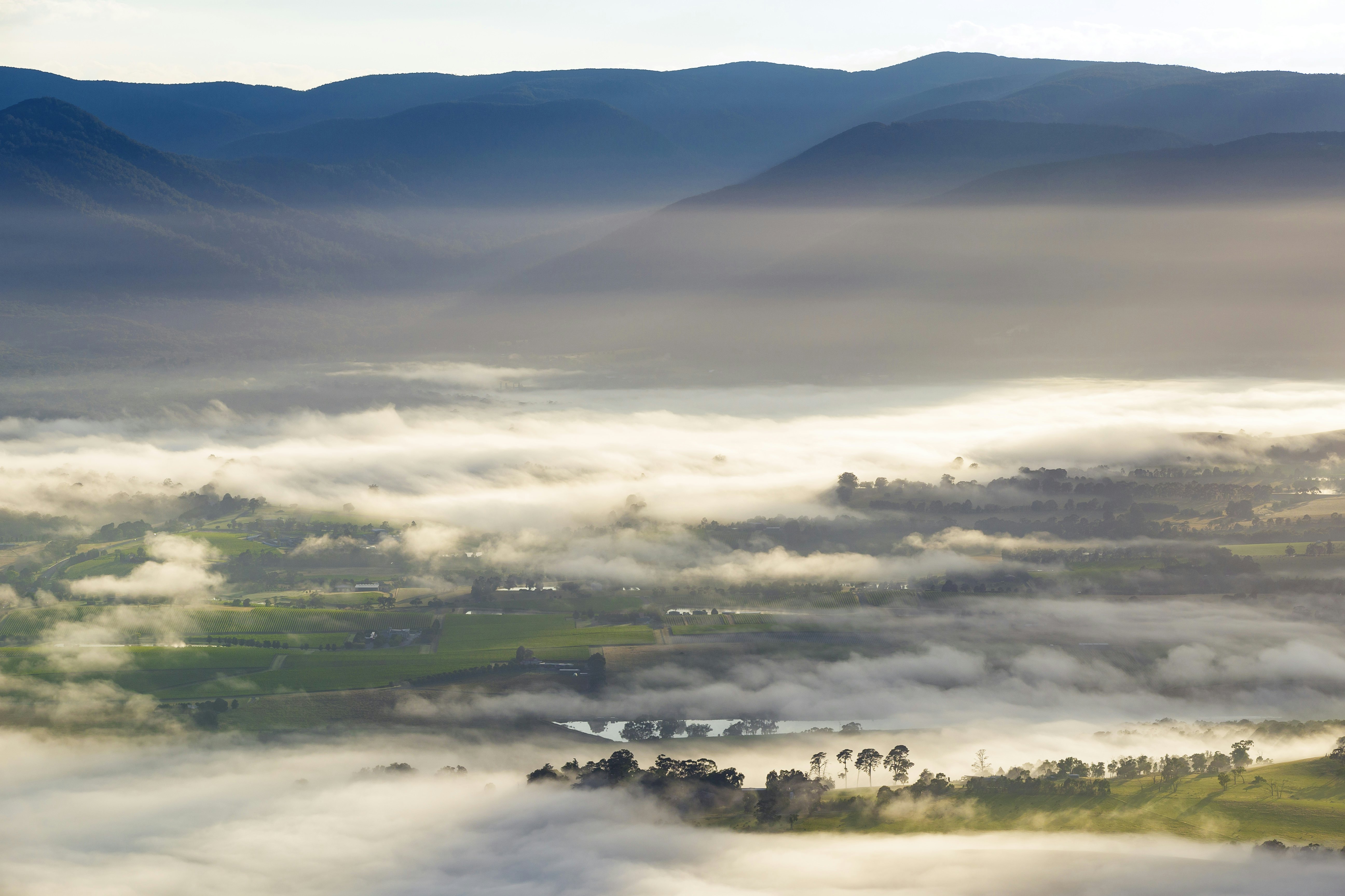 A mist rises over vineyards, field and mountains