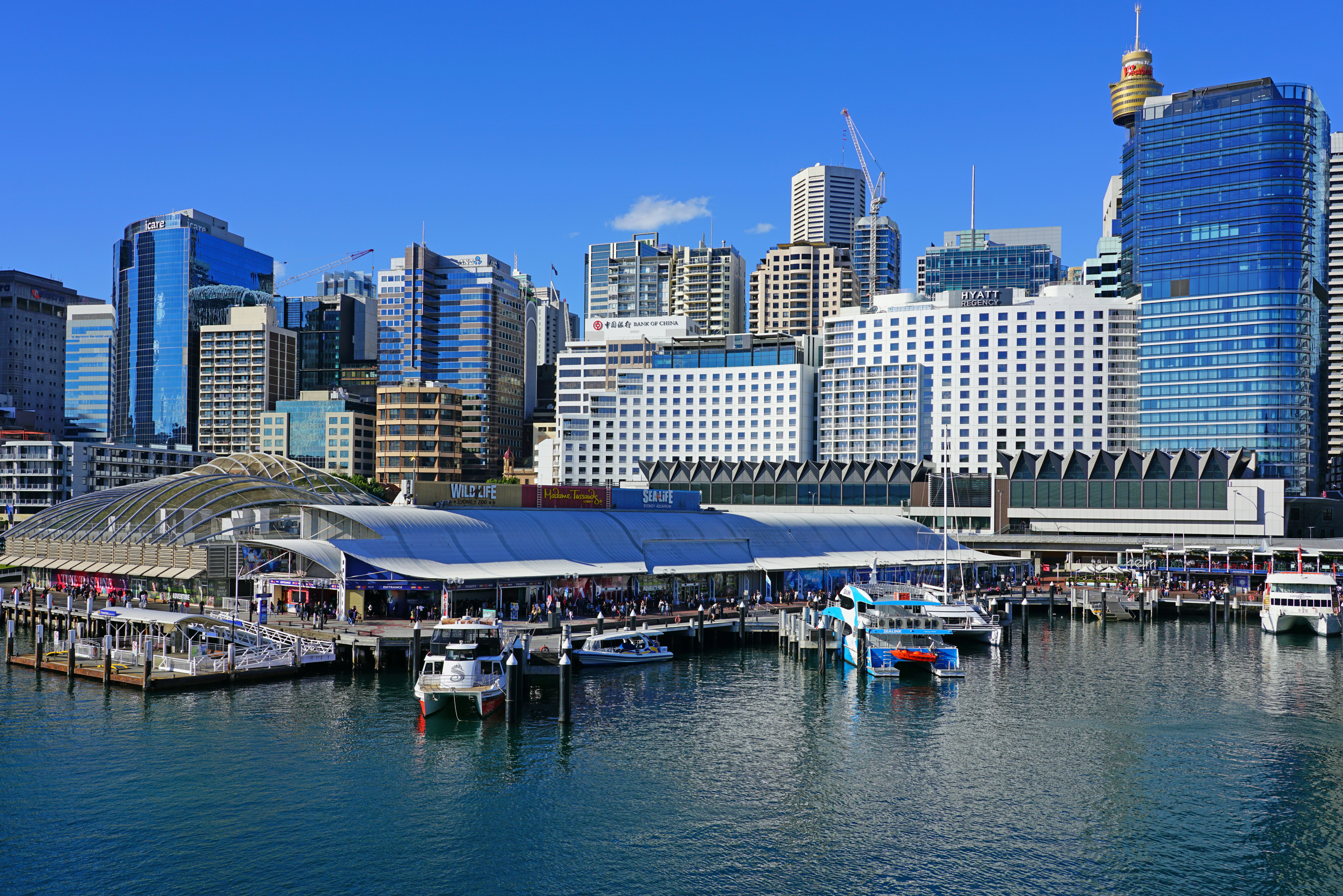 A harbor waterfront lined with bars, restaurants and attractions. High-rise buildings stand behind.
