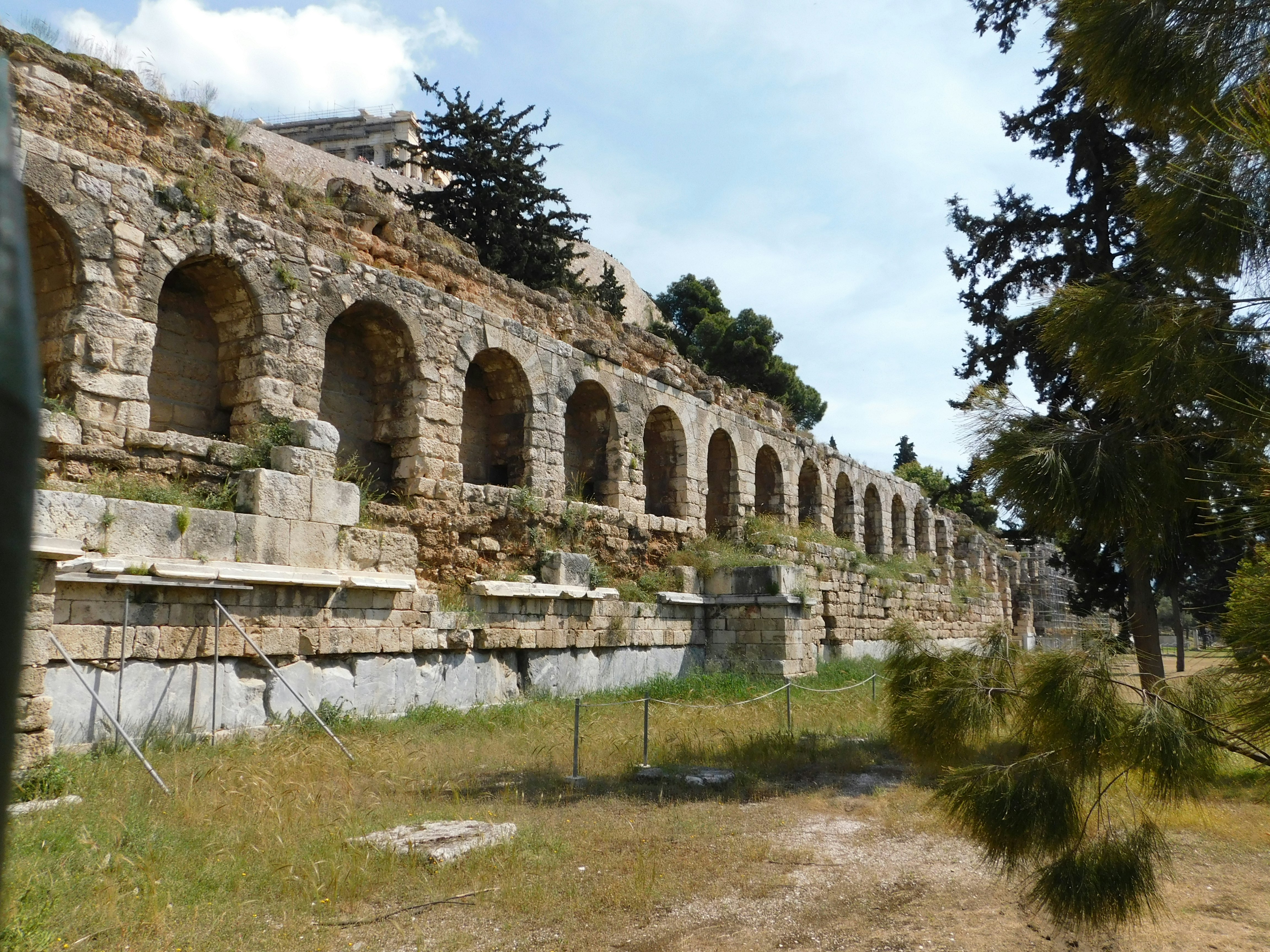Stone ruins with curved archways in a grassy field on a sunny day.
