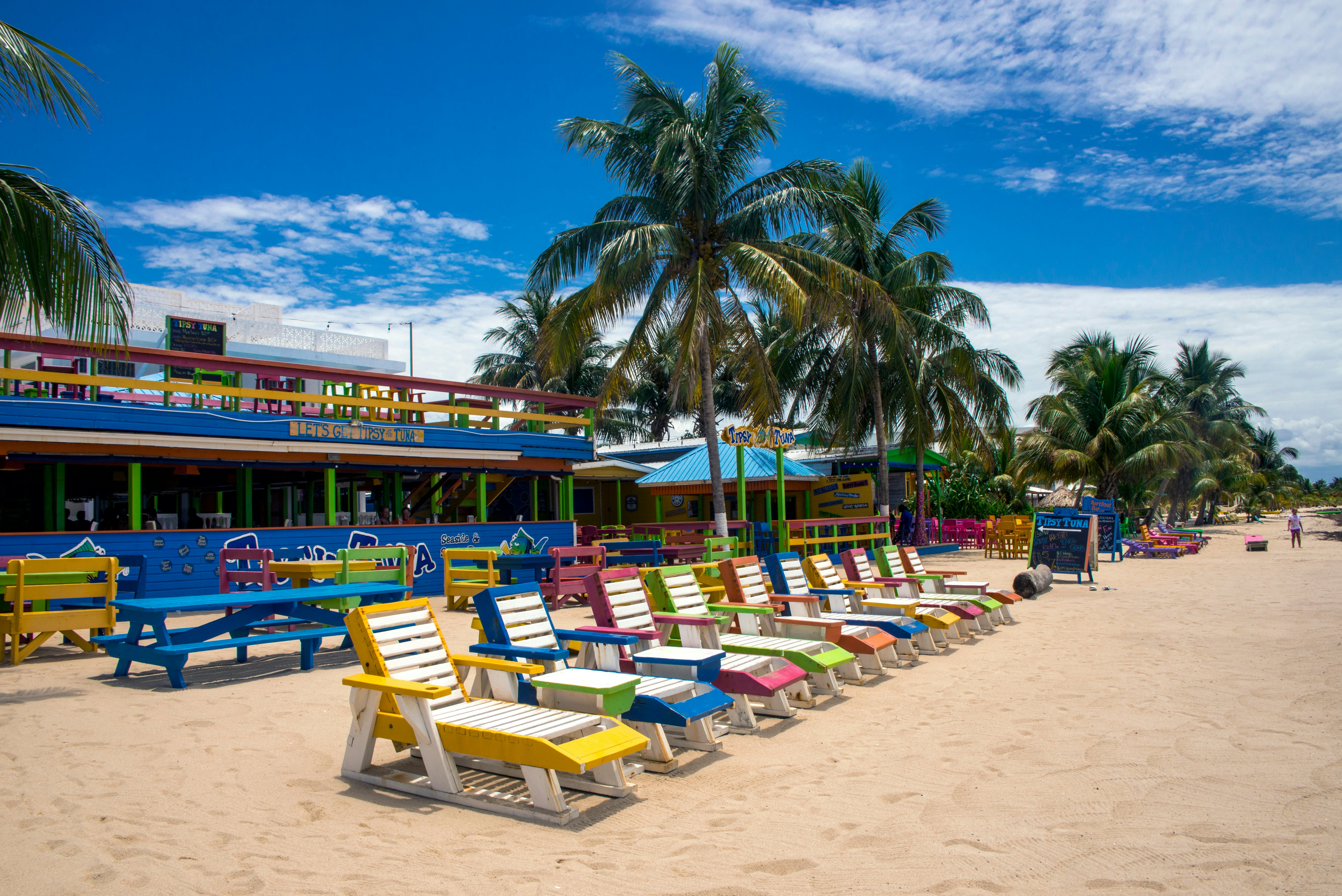 A sandy beach with brightly coloured sunloungers in a row outside a restaurant.