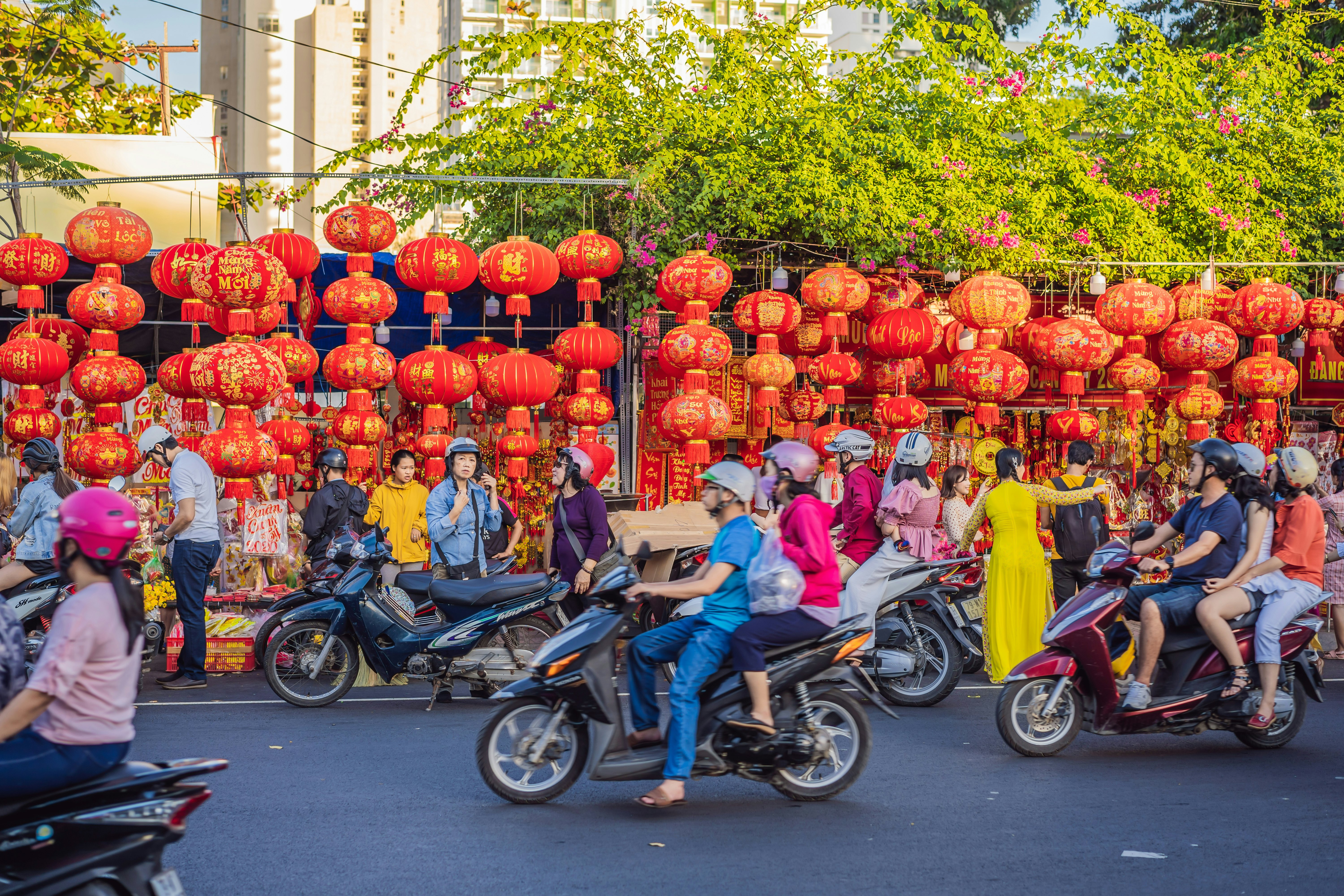 people on motorbikes riding in front of Lunar New Year red decorations