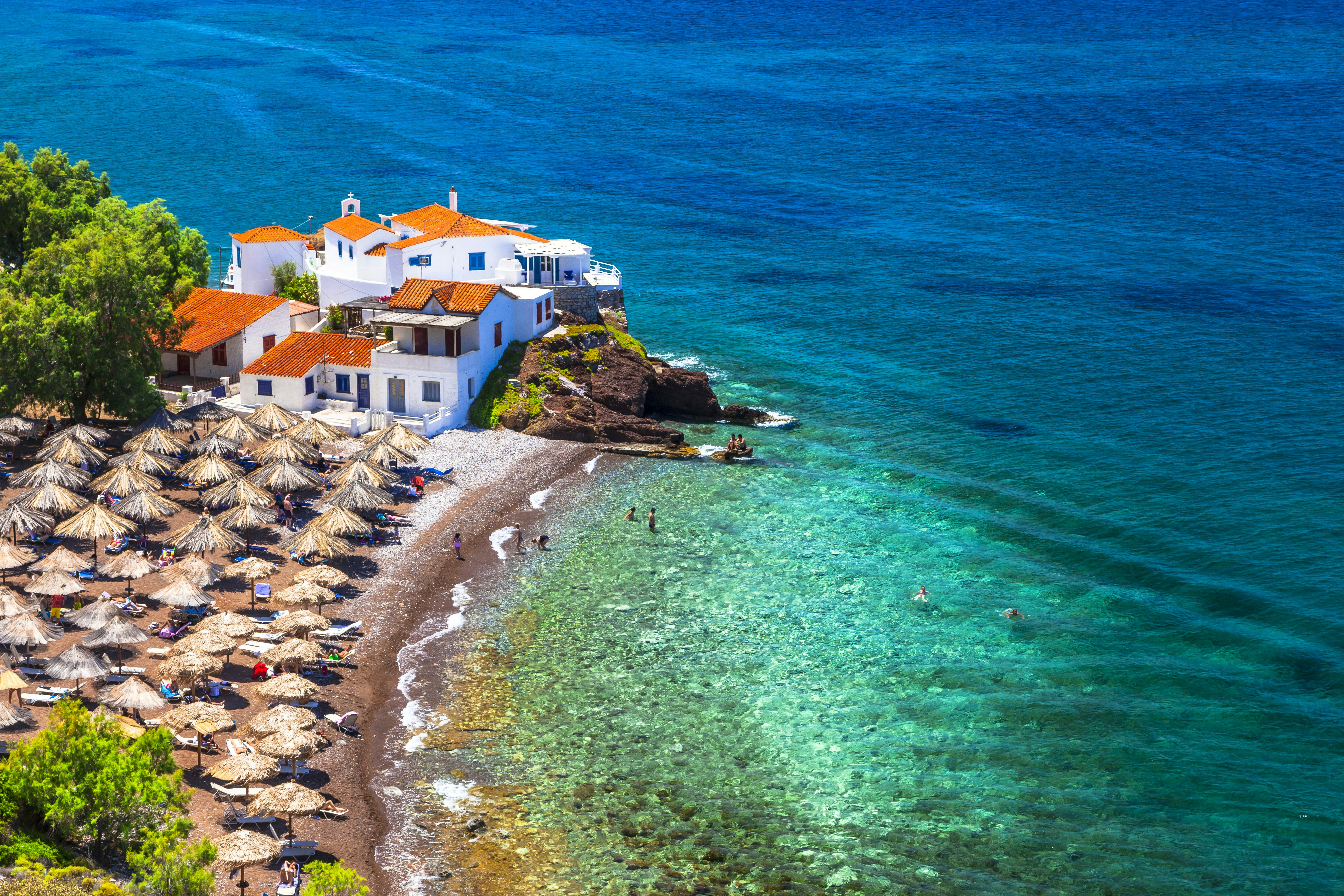 umbrellas against sand and white building with sea