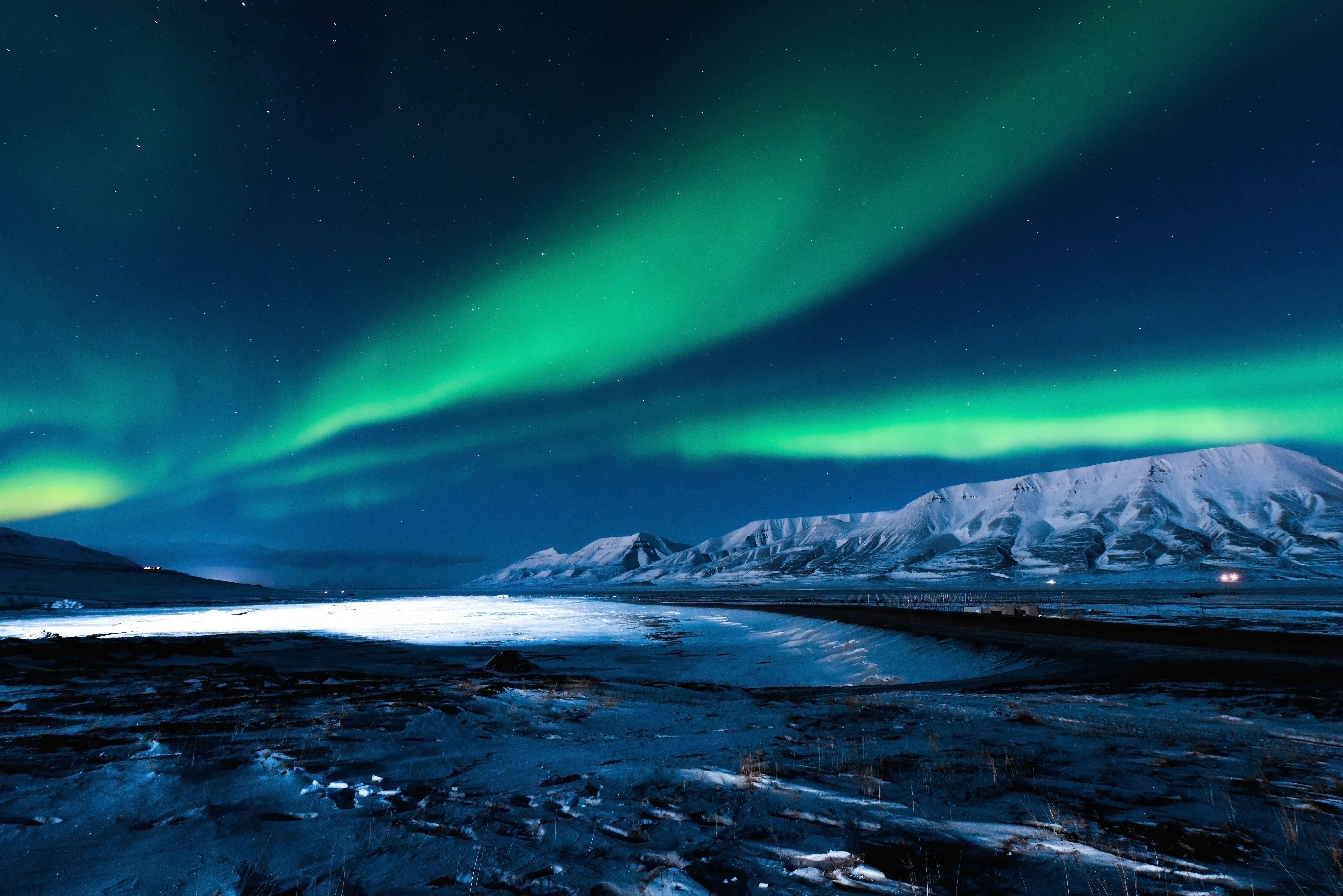 Green streaks of light over a dark snowy landscape.