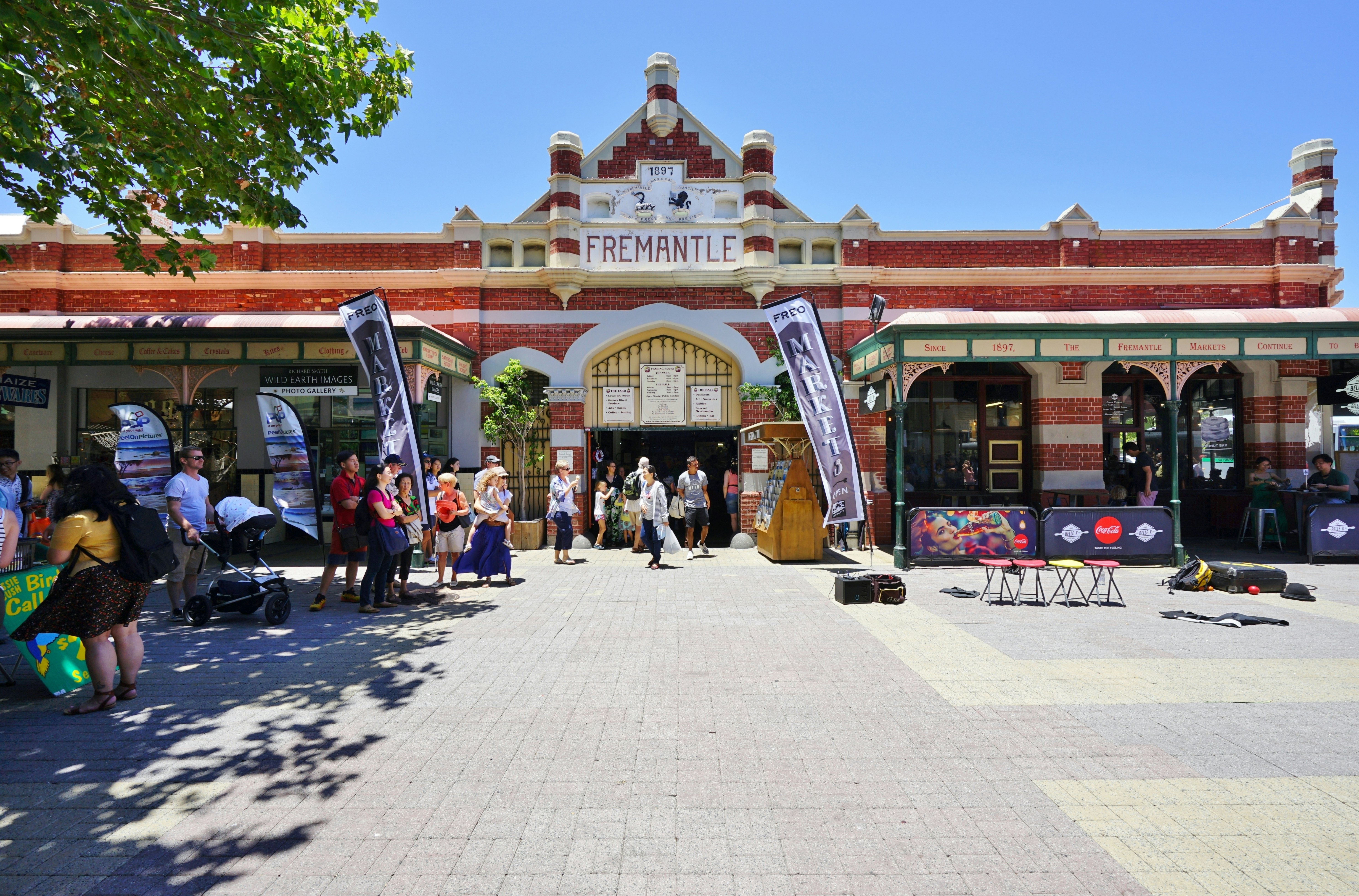 People near the entrance to a large red-brick market building.