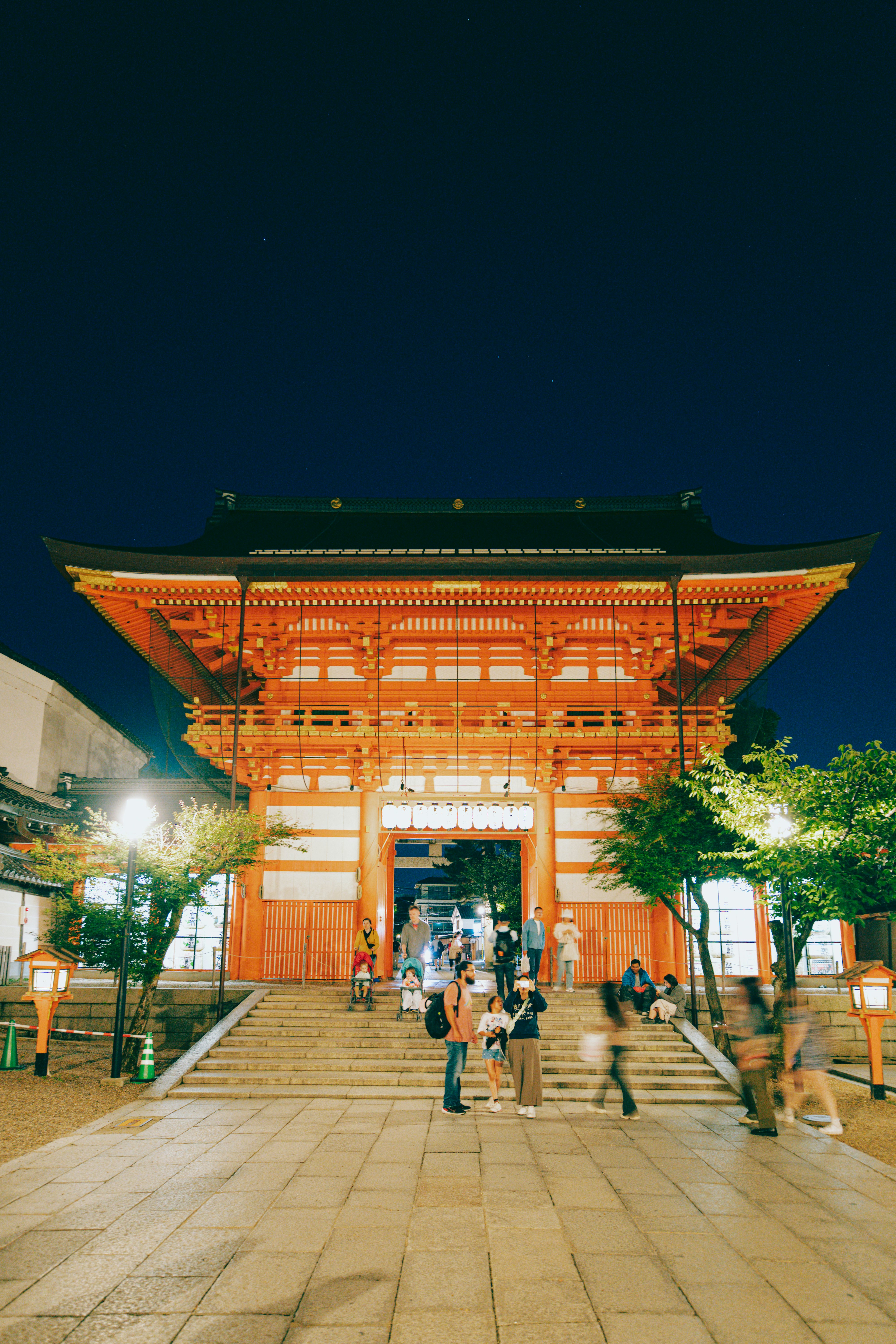 A family with two strollers bump their way down steps in front of a shrine.