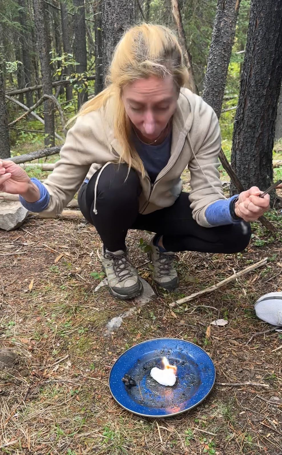 A woman lights a fire on a blue plate.