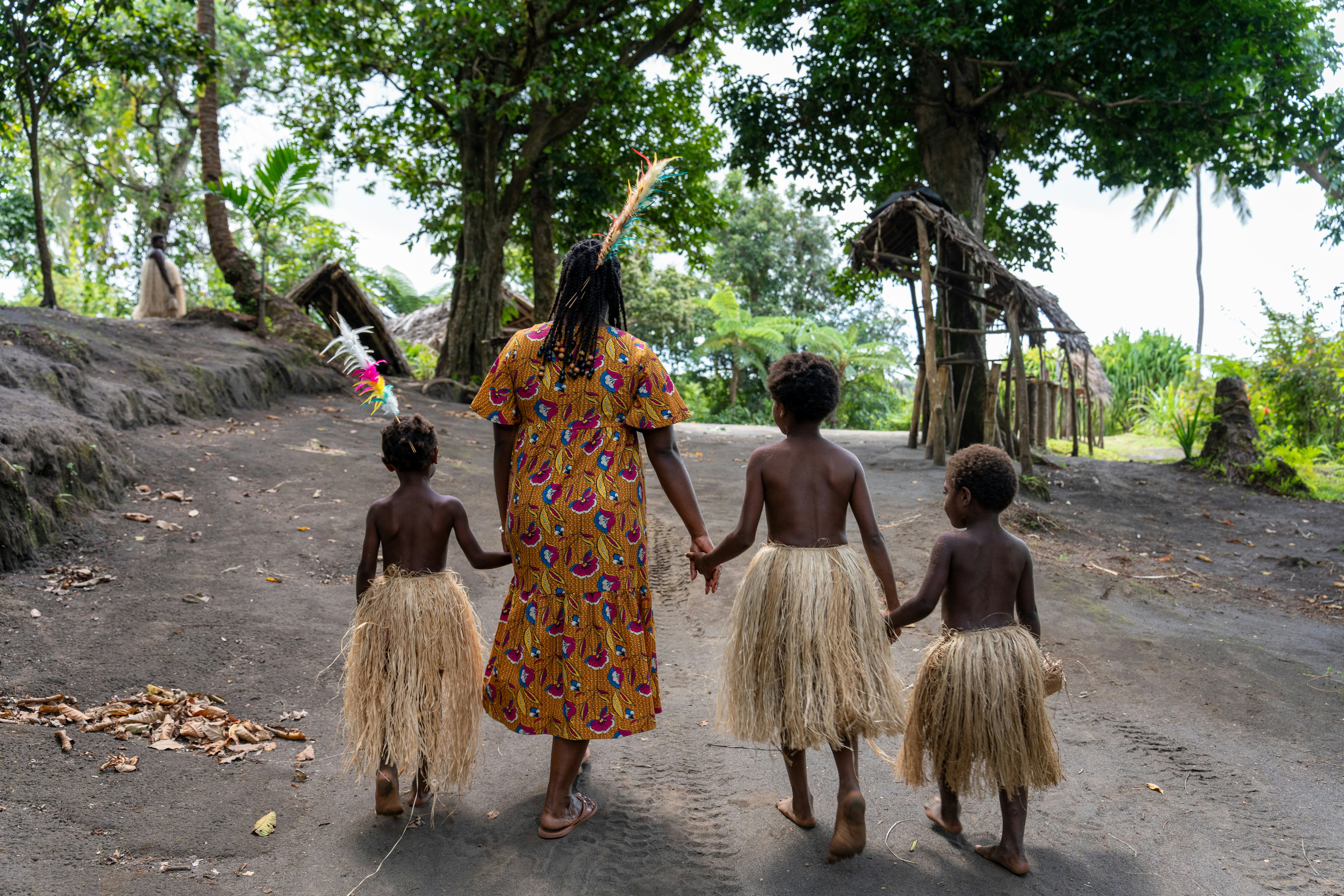 A woman walking with children with straw skirts