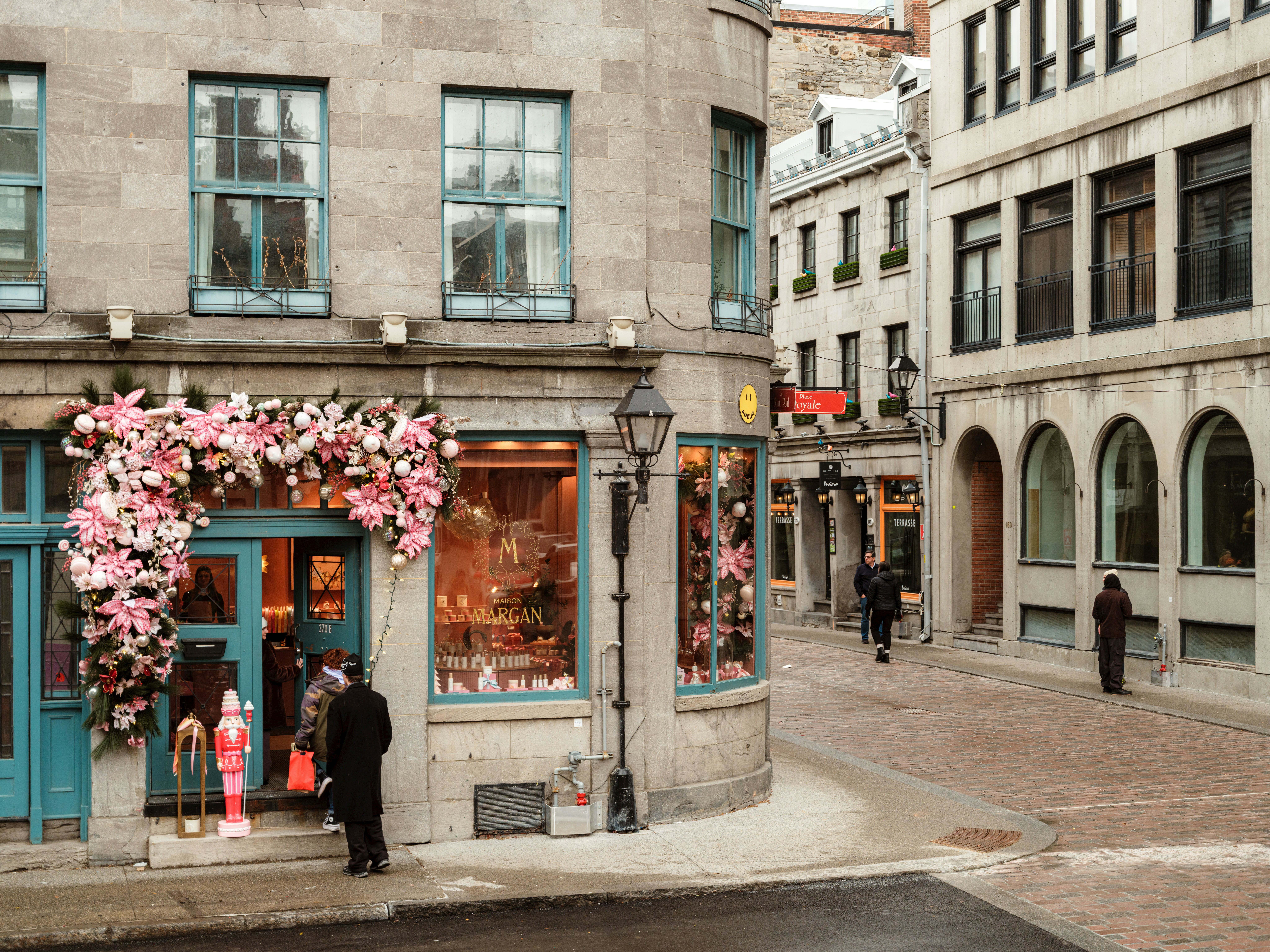 A view of a decorated store on a corner with people in the street wearing jackets