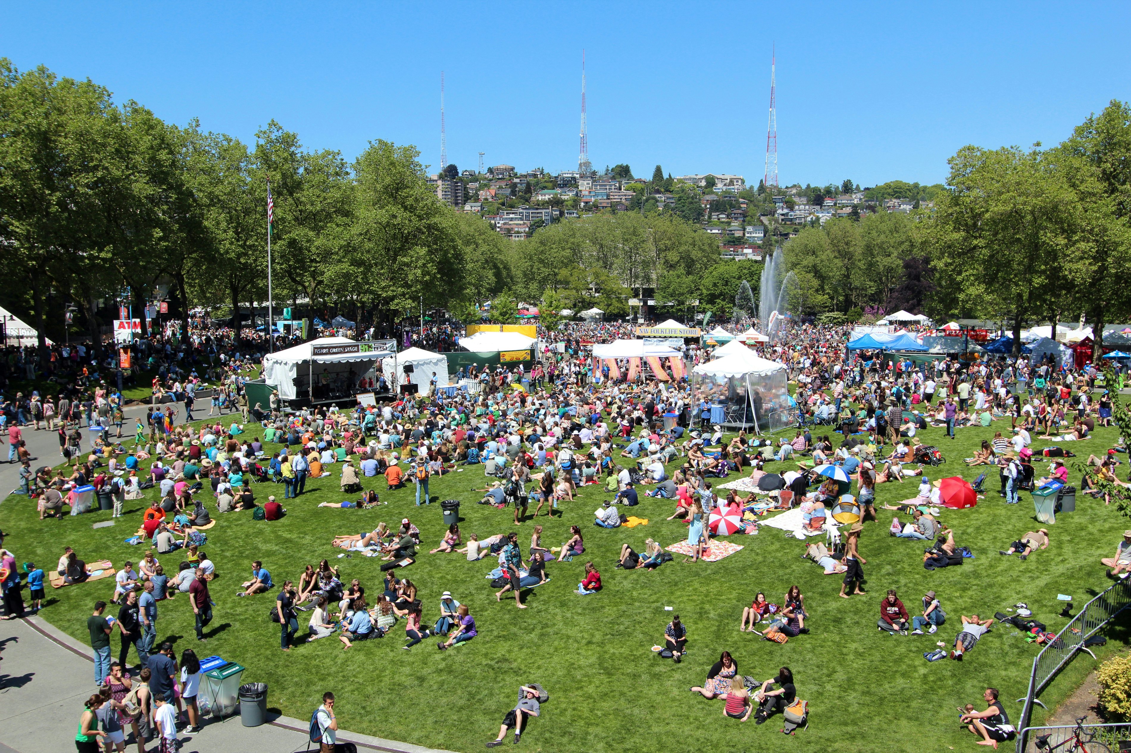People and tents dot the grassy grounds of an open park area