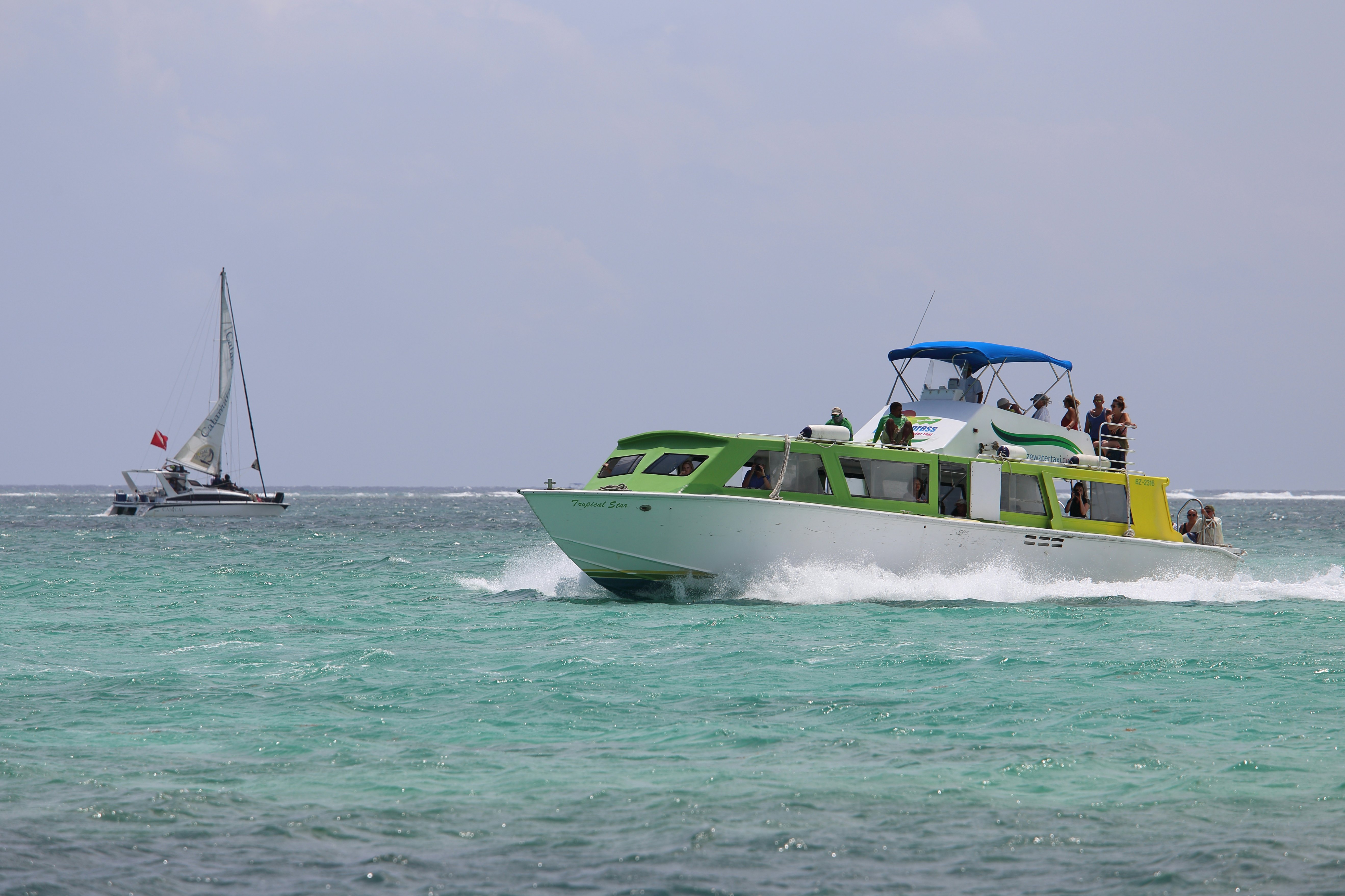 A ferry boat glides through the water past a small sailboat.