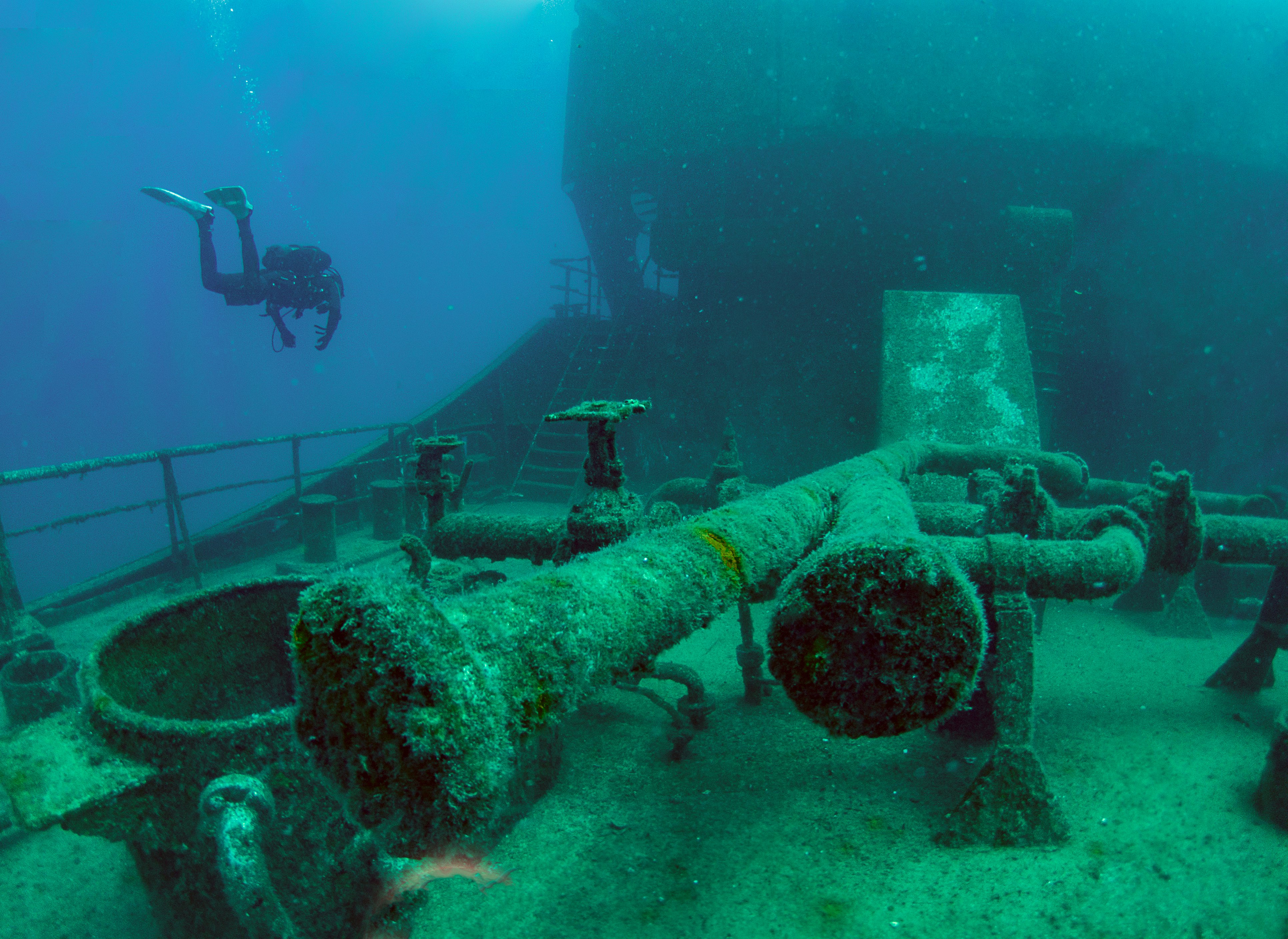 A scuba diver swims near the wreck of a tanker