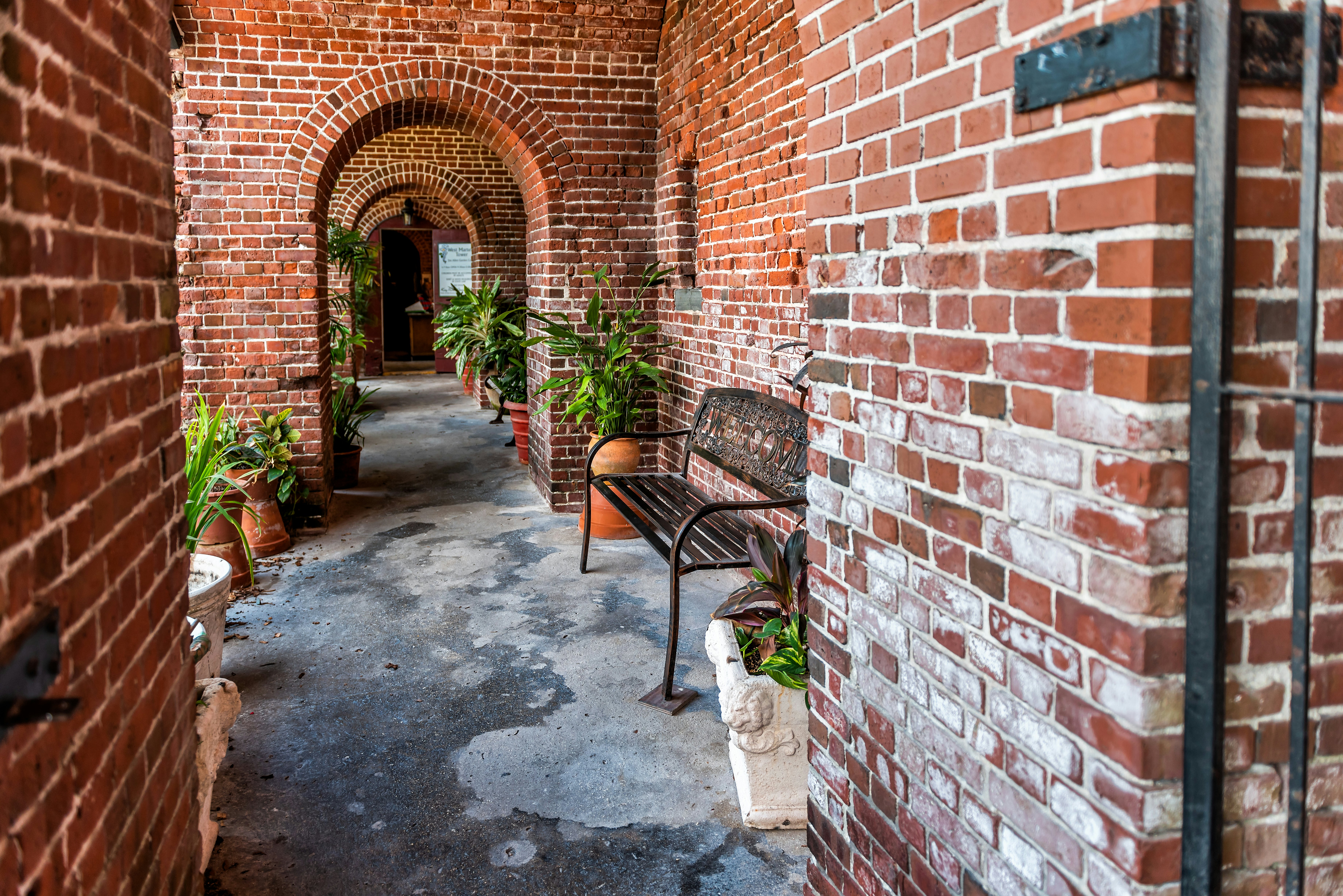 Plants and benches line a passageway through a historic building constructed of bricks.