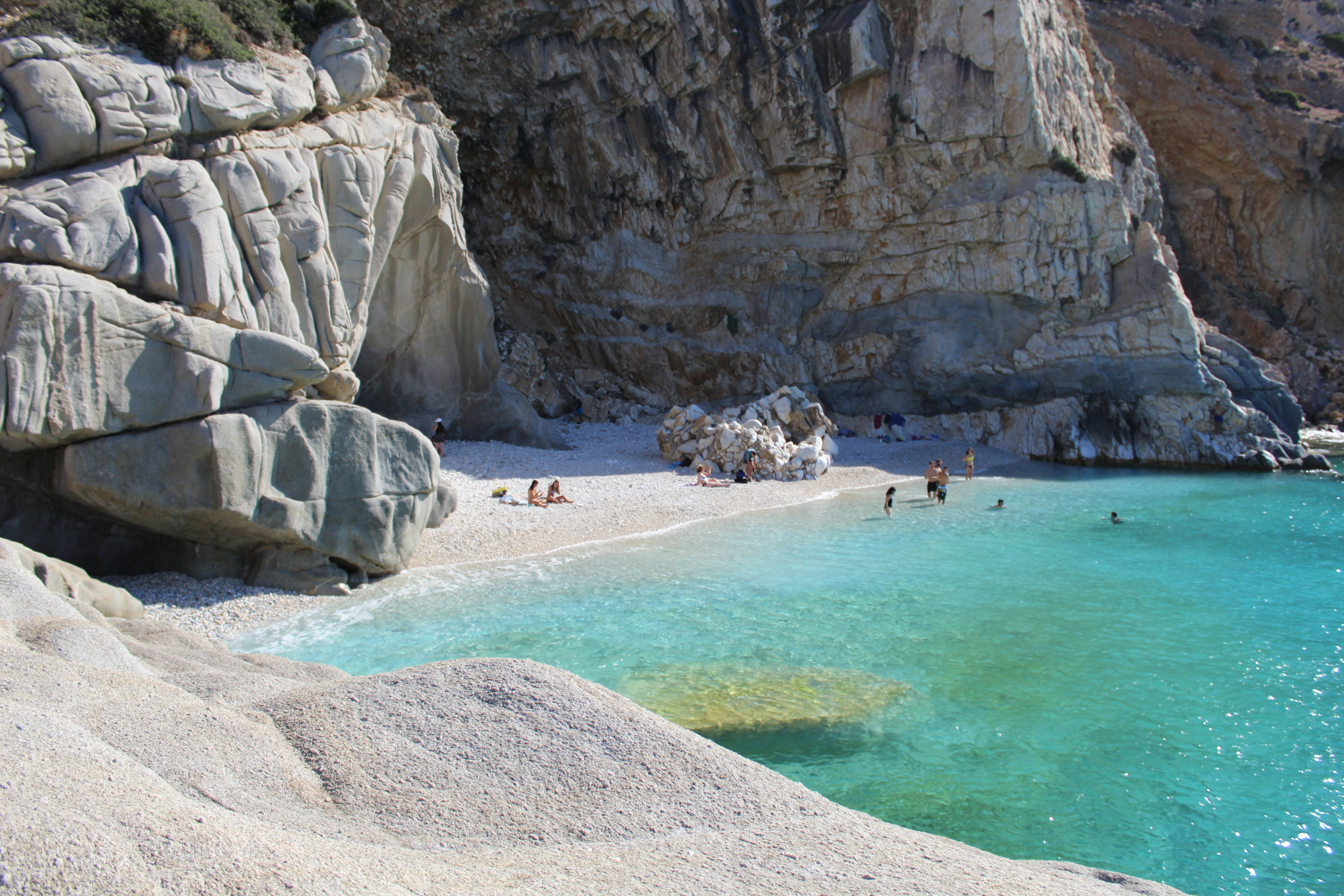 People on a small beach with large white rocks
