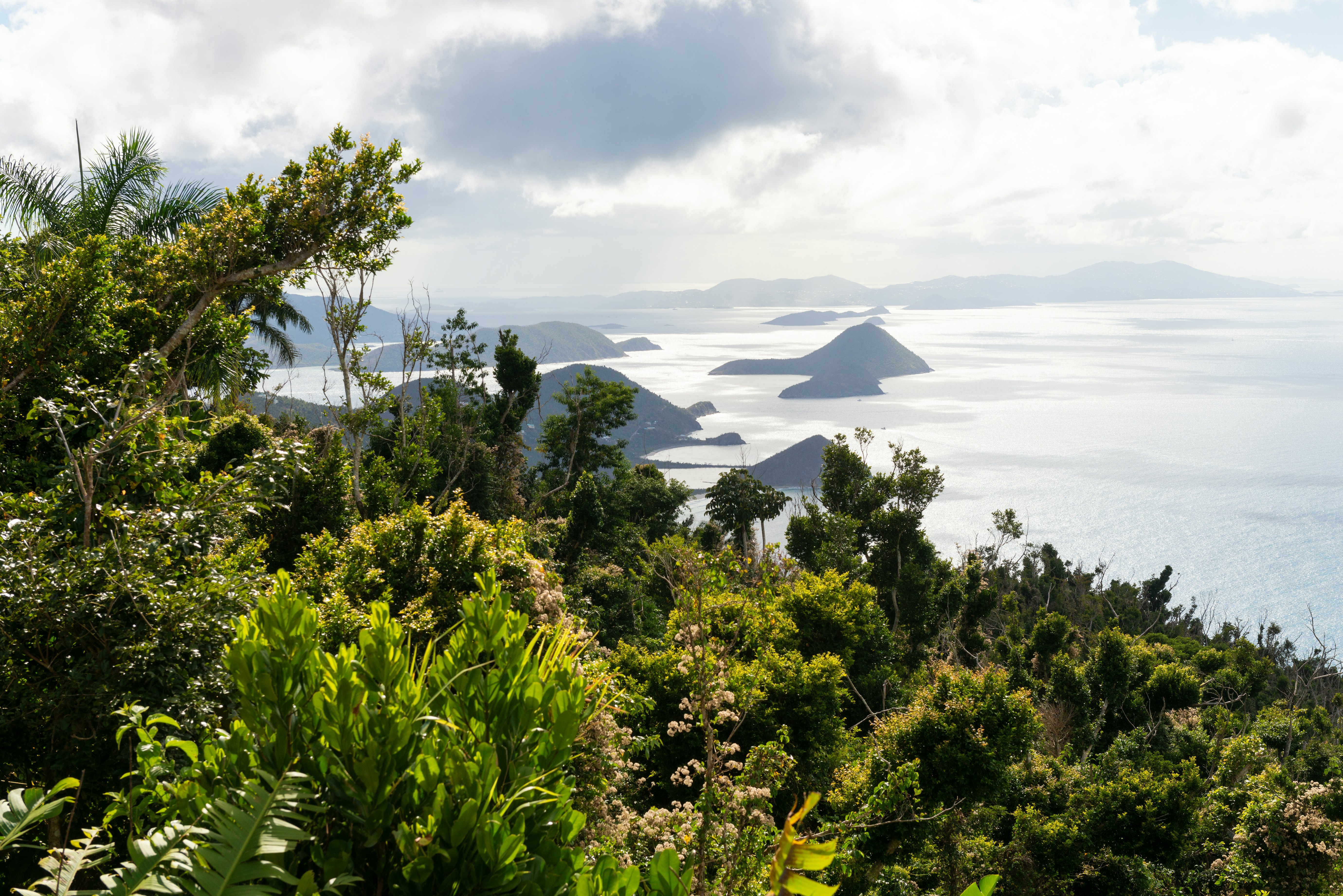 Islands are seen in the sea from the top of a lush hilltop on a tropical island.