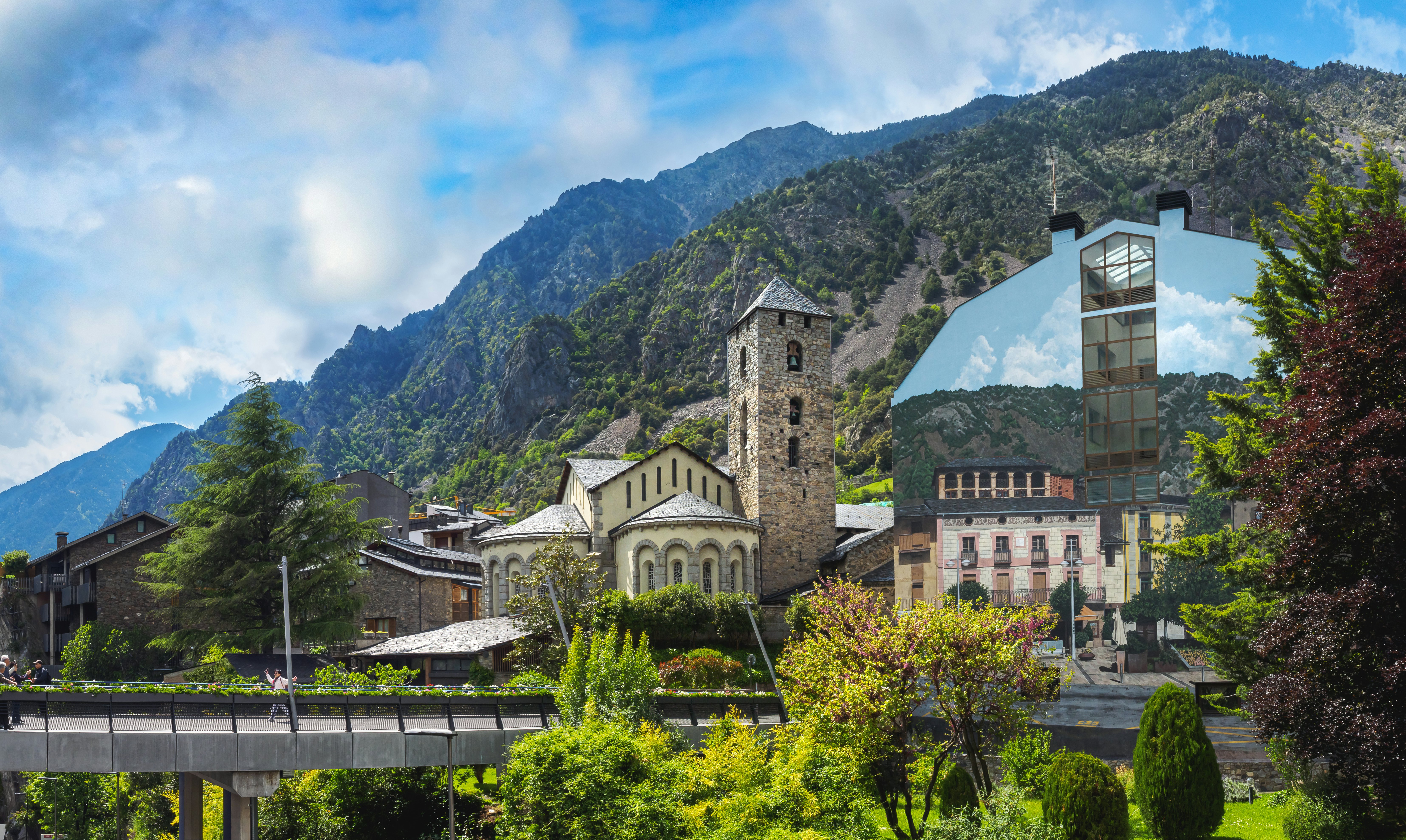 A church nestled in lush green mountains with a bridge in front