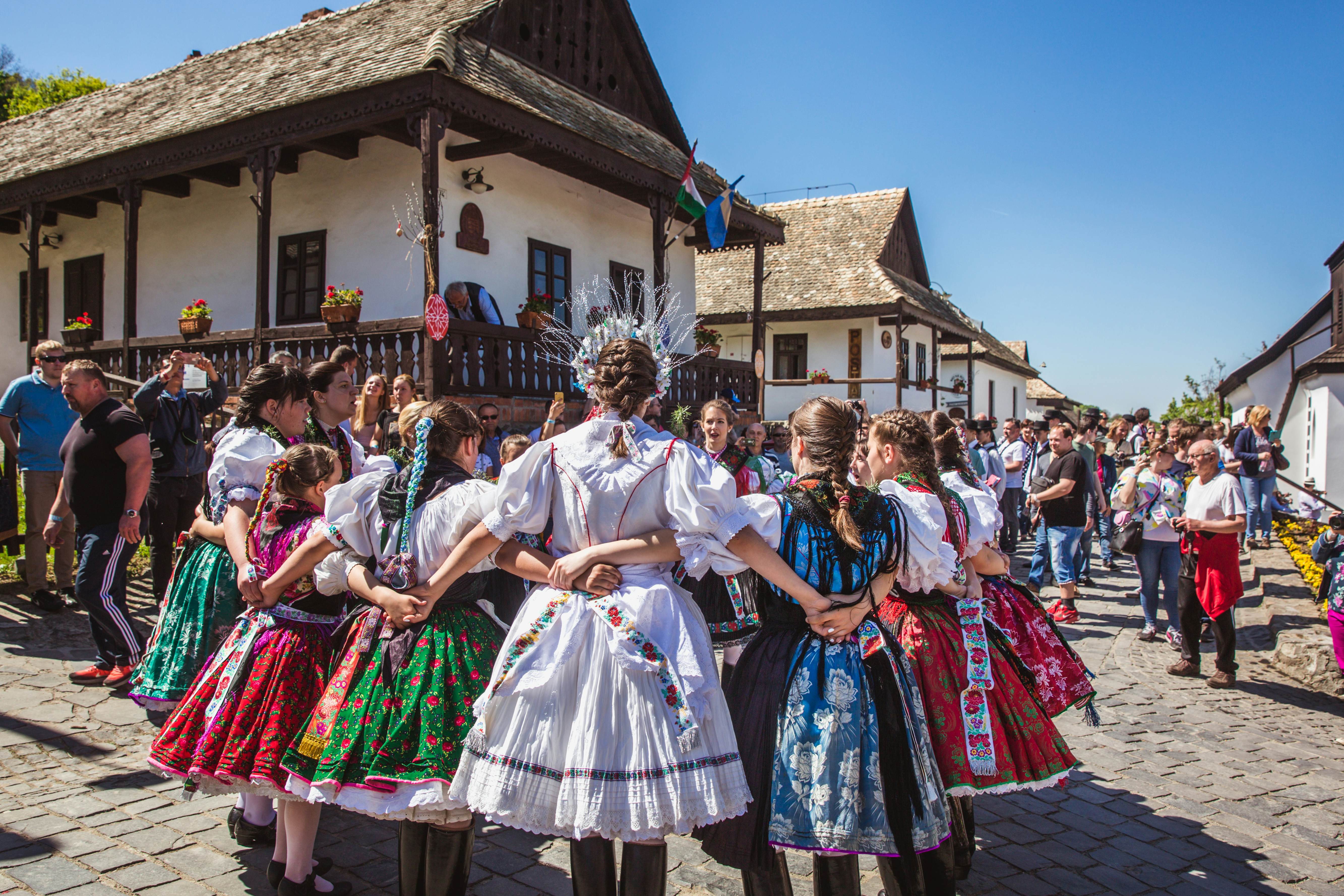 People in festival dress clasp arms in a circle