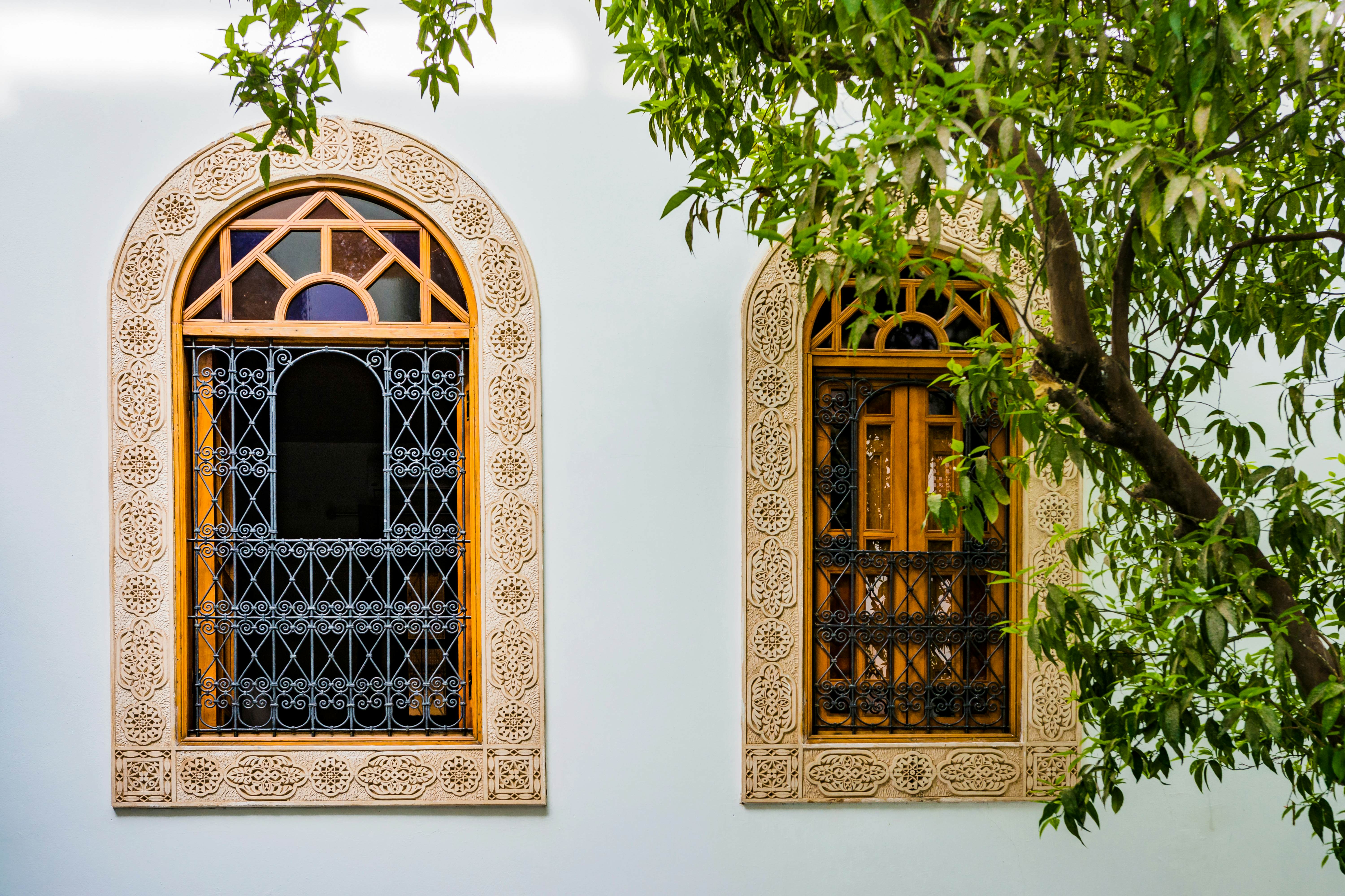 Two arched windows with decorated grills and carvings around the perimeter.
