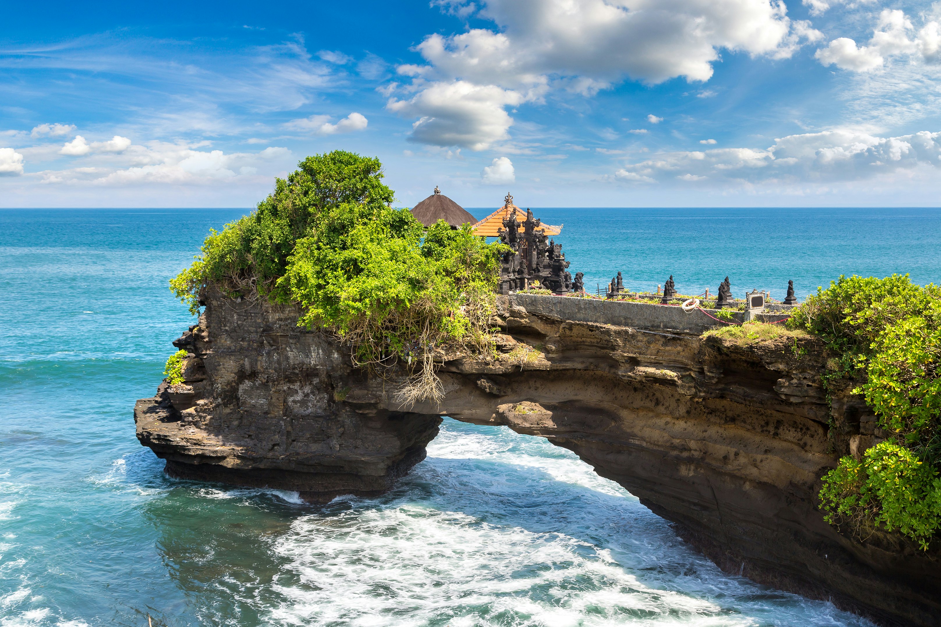 A temple is built on a rock formation that extends over the sea.