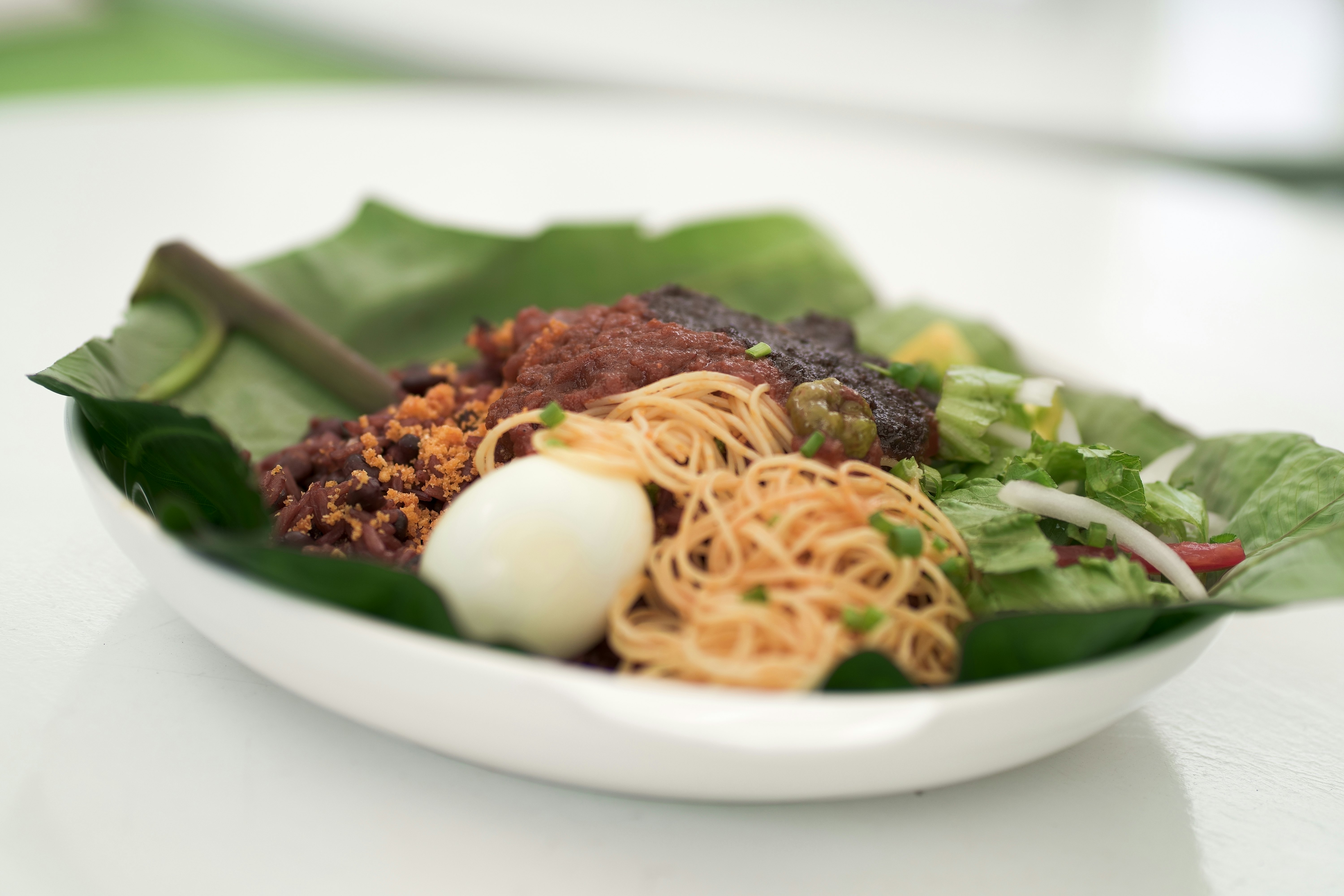 Waakye, Ghanaian Cuisine wrapped in green leaves. Colored Rice with Pepper, Shito and Spaghetti