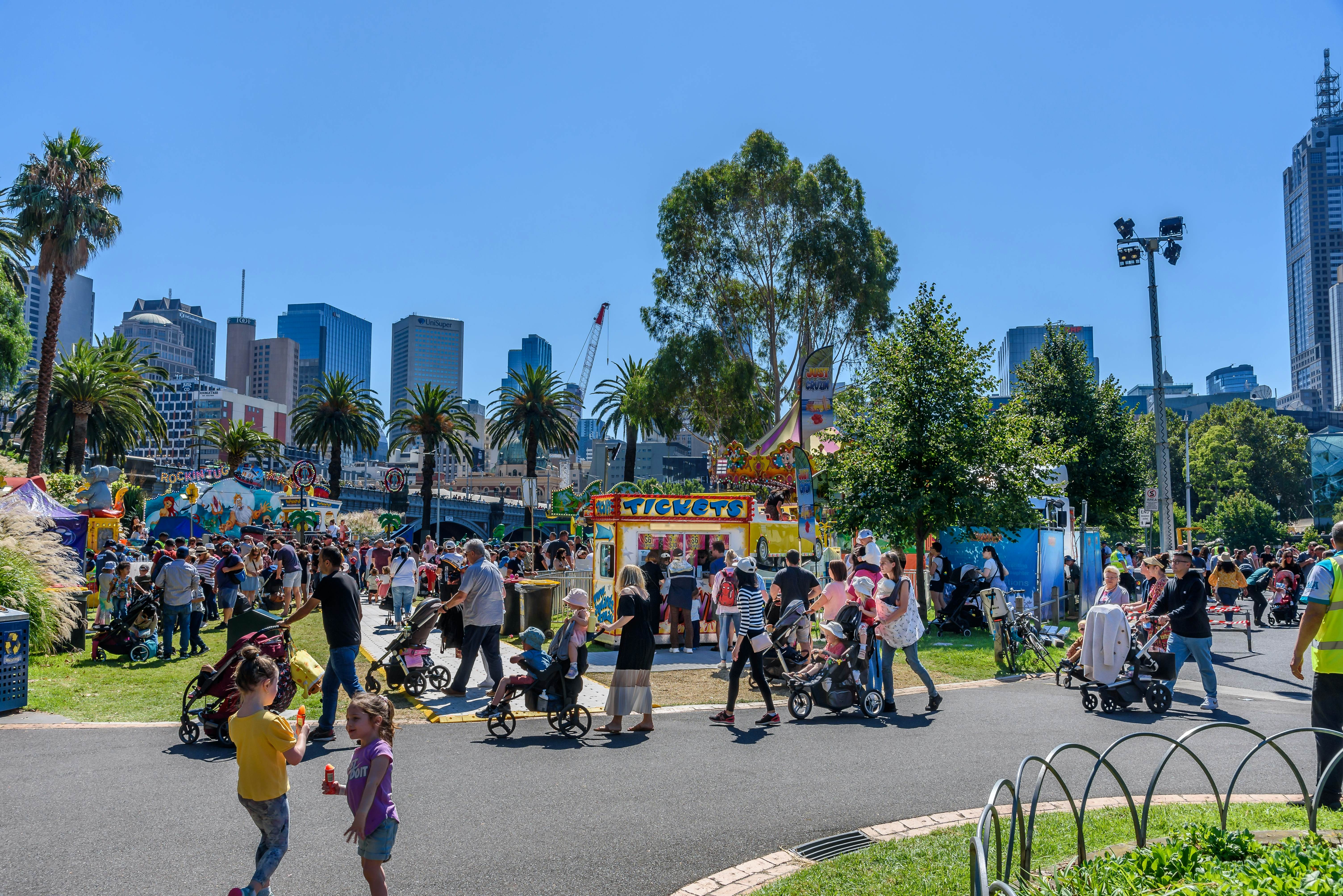 Melbourne, Victoria, Australia, March 12th, 2022: Parents and children line up to buy tickets for rides at the Moomba Carnival on the banks of the Yarra River with the city buildings in the background, License Type: media, Download Time: 2025-12-02T09:31:48.000Z, User: sashabrady26, Editorial: true, purchase_order: 65050 - Digital Destinations and Articles, job: Lonely Planet, client: Best things to do in Melbourne with kids, other: Sasha Brady