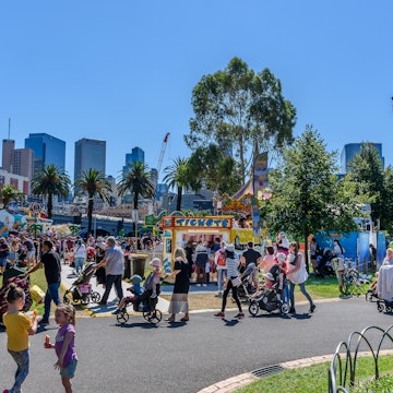 Melbourne, Victoria, Australia, March 12th, 2022: Parents and children line up to buy tickets for rides at the Moomba Carnival on the banks of the Yarra River with the city buildings in the background, License Type: media, Download Time: 2025-12-02T09:31:48.000Z, User: sashabrady26, Editorial: true, purchase_order: 65050 - Digital Destinations and Articles, job: Lonely Planet, client: Best things to do in Melbourne with kids, other: Sasha Brady