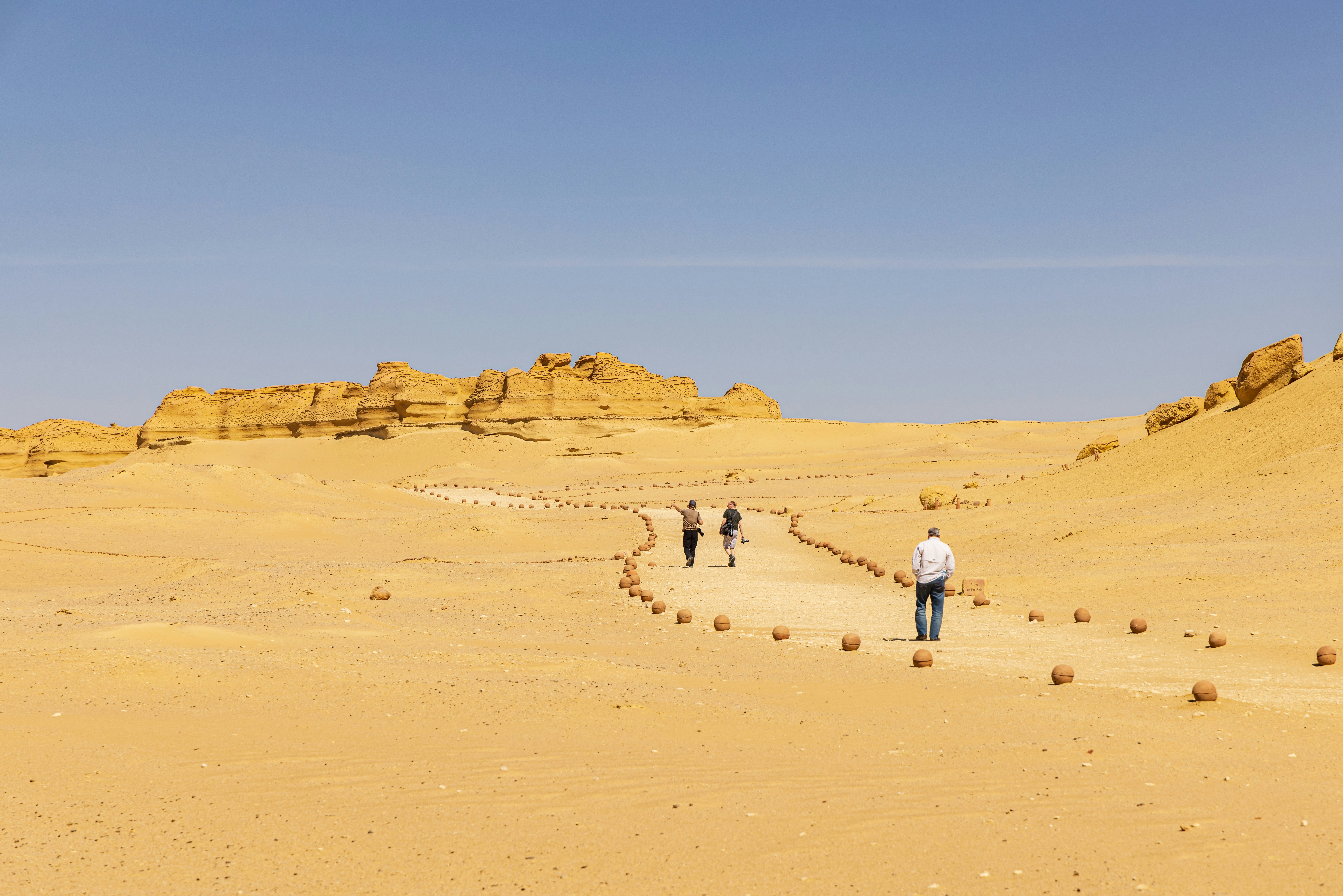 People follow a trail marked out by rocks in a desert landscape.