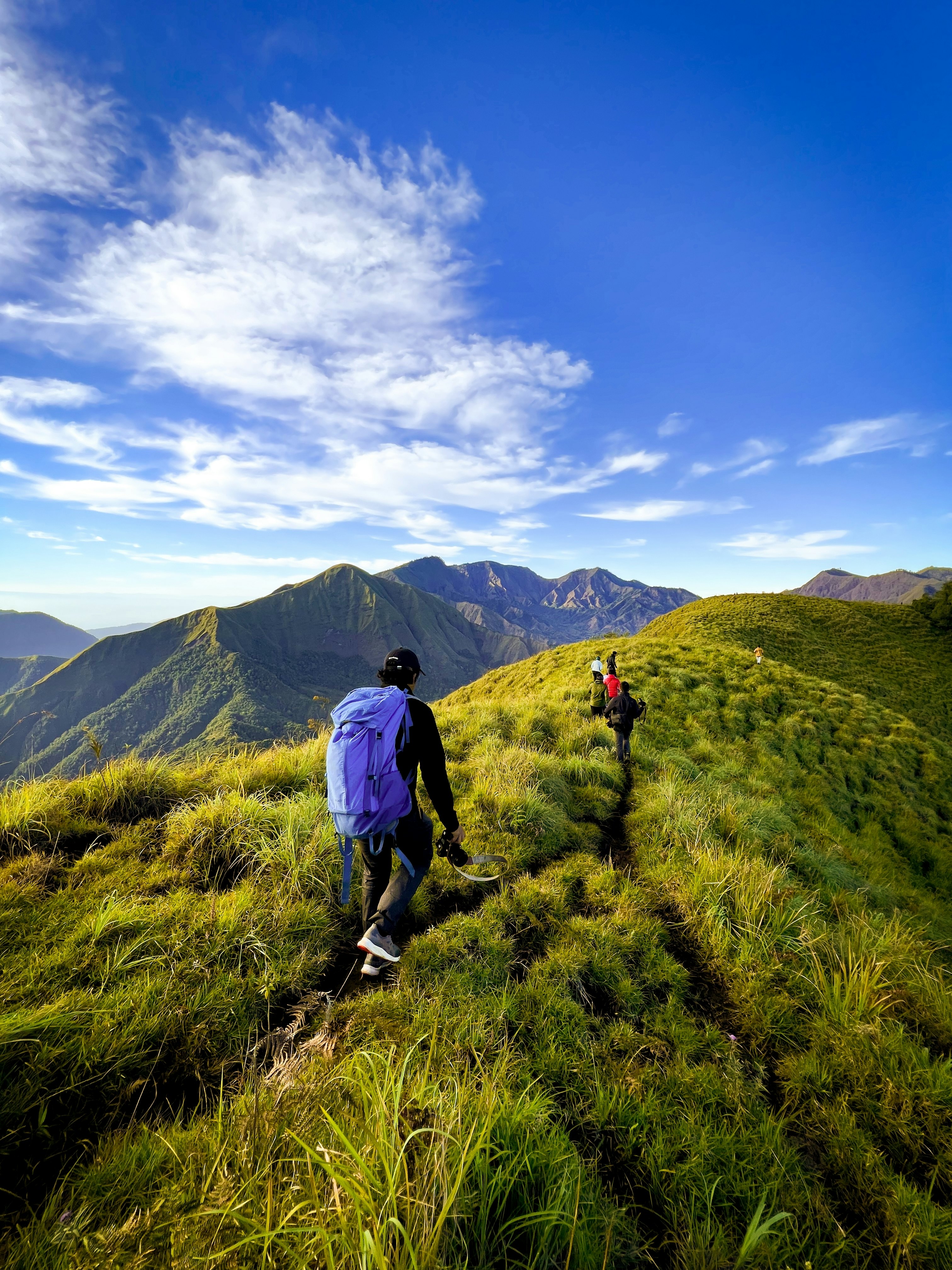 People hiking up a mountain, with other mountains nearby