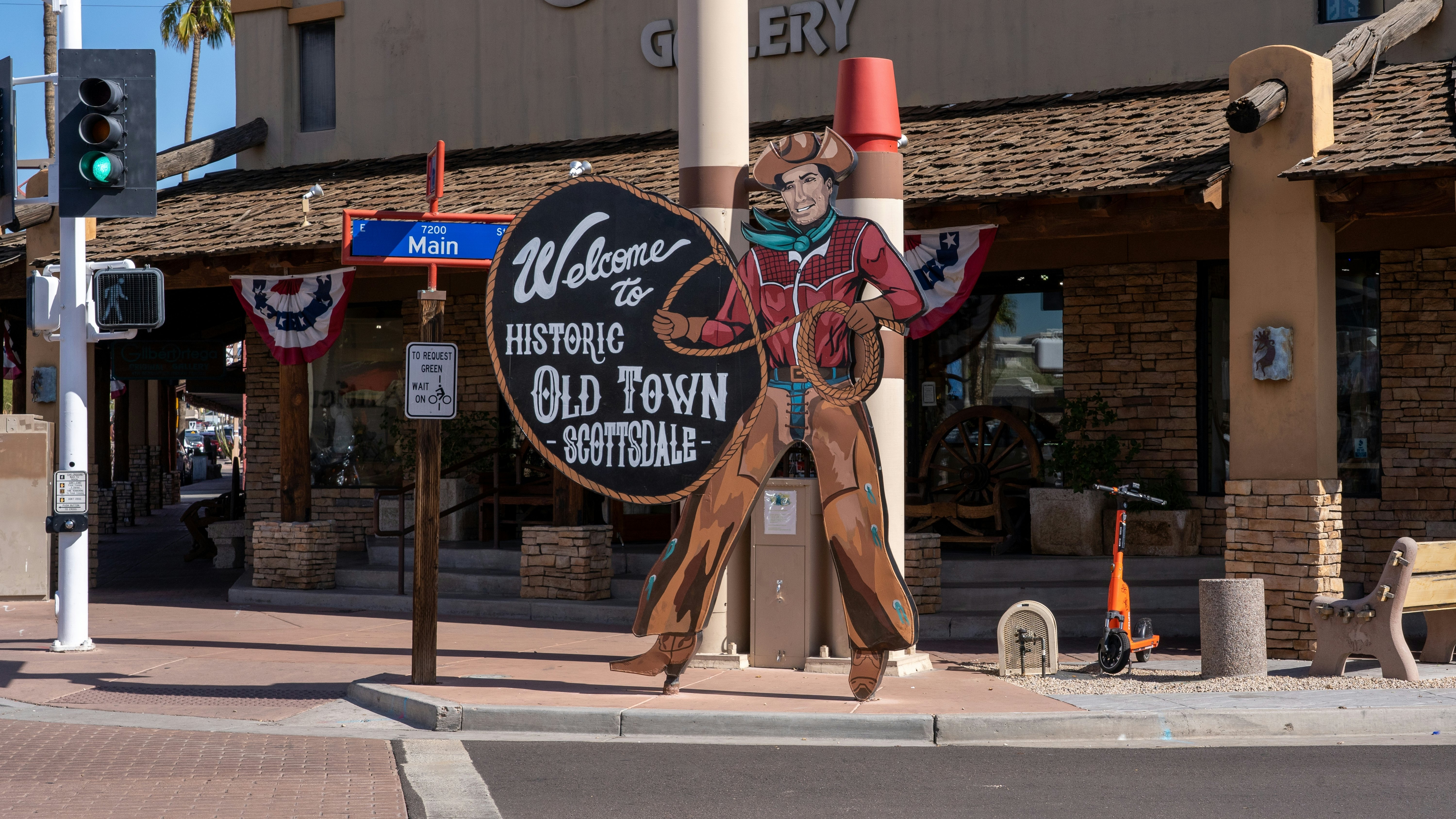 A cowboy sign in front of Main Street in Old Town Scottsdale