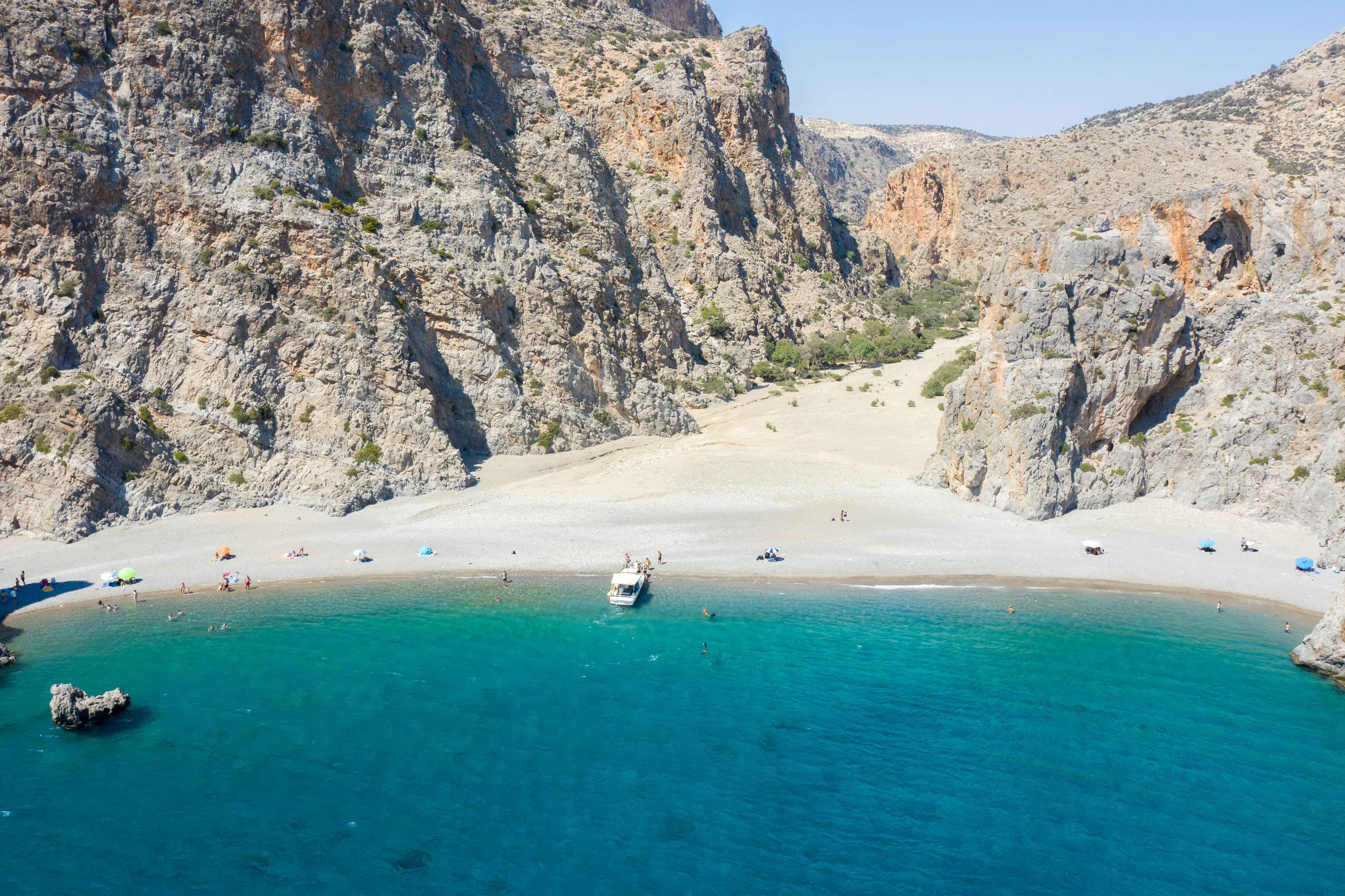 A sparsely populated beach with craggy mountains near its shore
