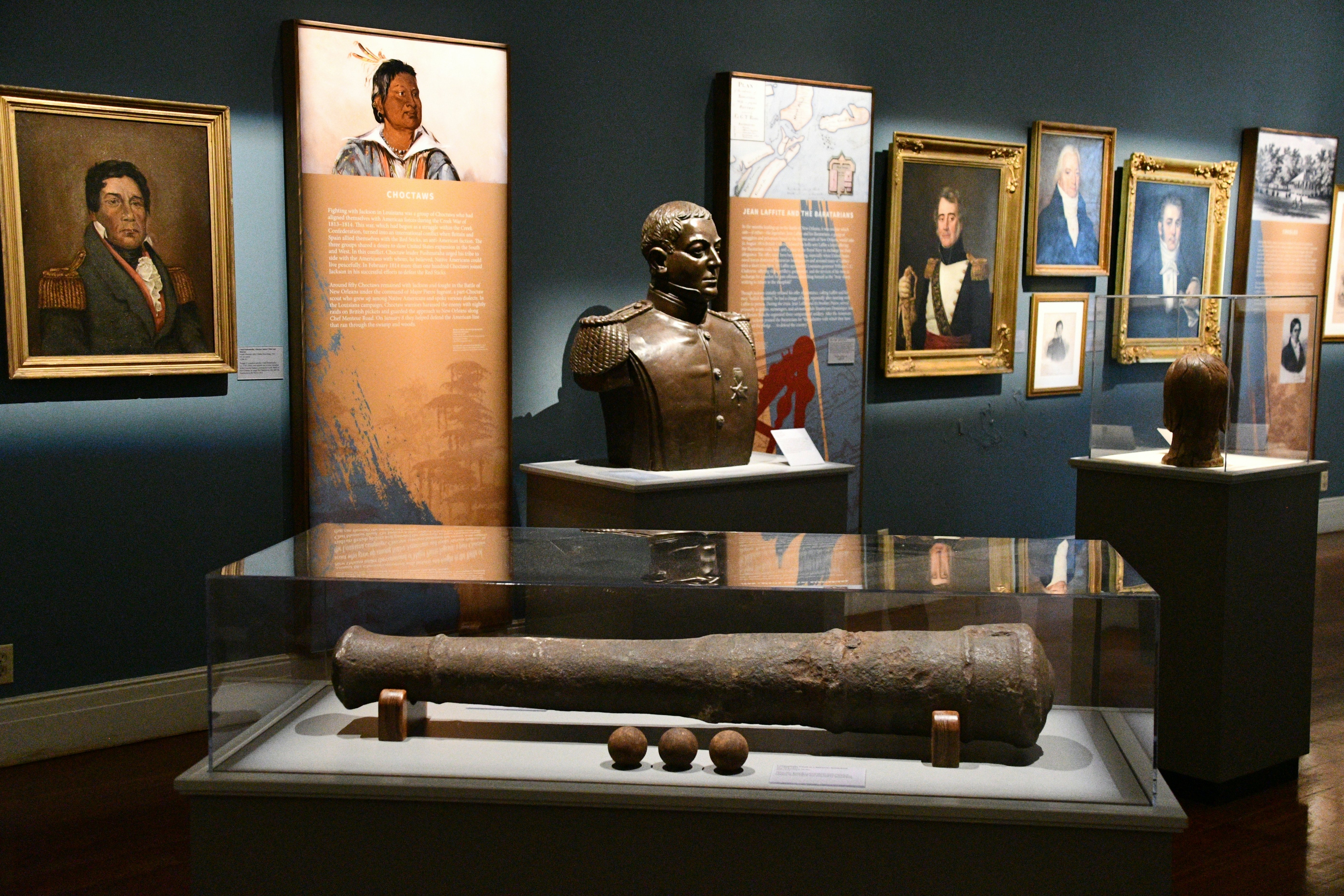 Paintings and artifacts are displayed in a gallery at a history museum.