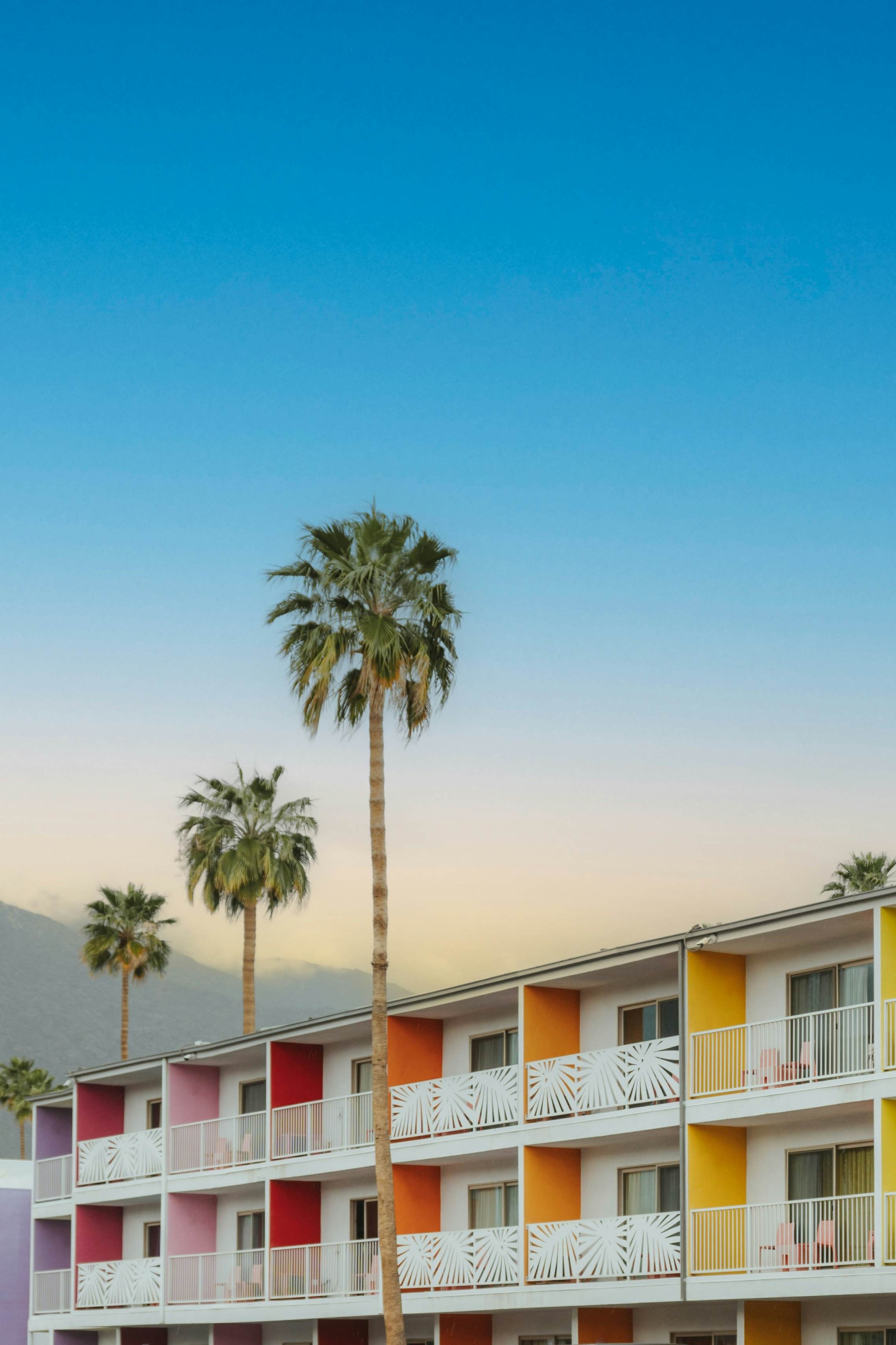 A colorful motel with palm trees in front of it. 