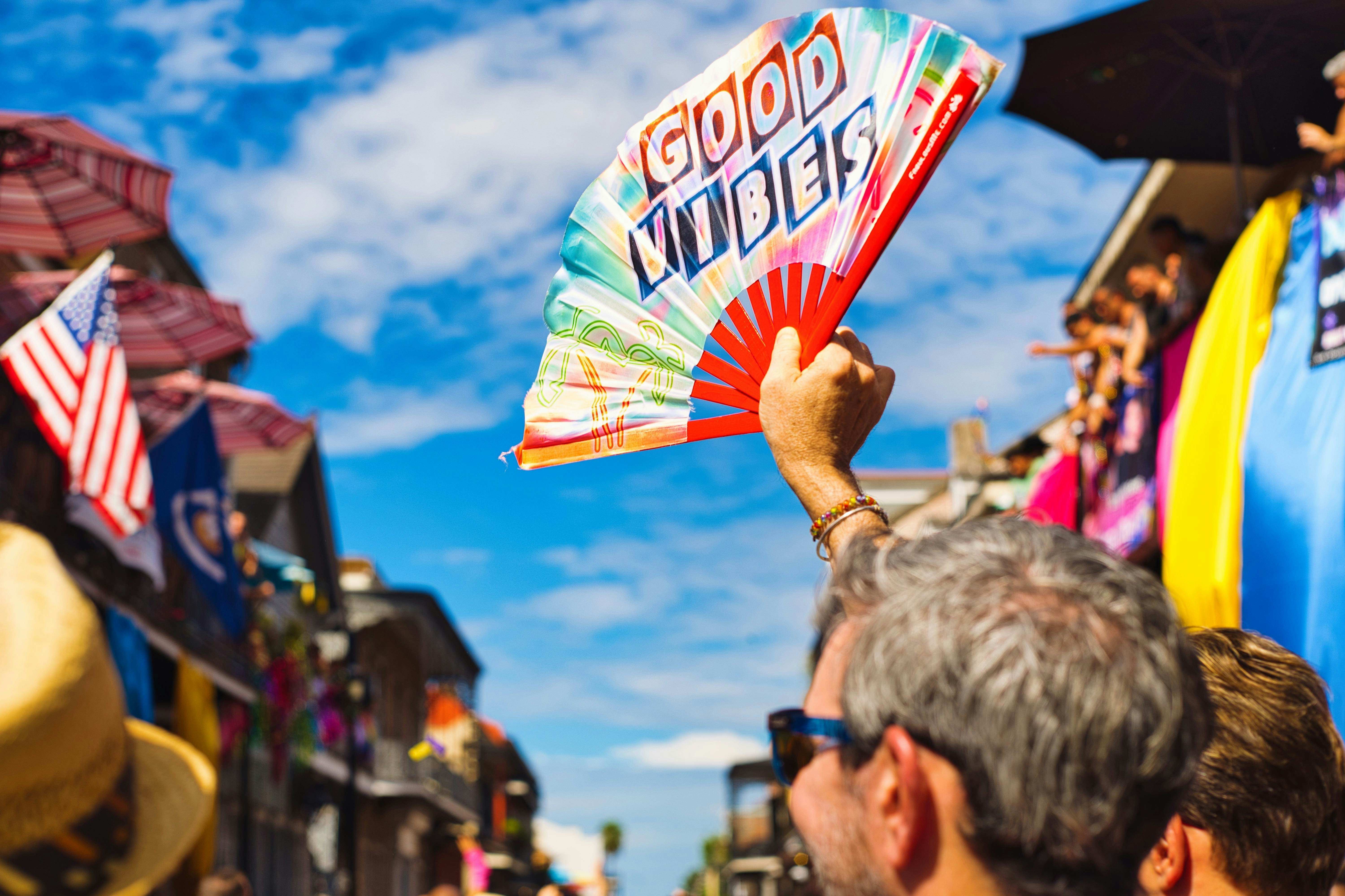New Orleans, LA - September 1, 2024: Person holds up a Good Vibes fan at Southern Decadence in New Orleans, License Type: media_digital, Download Time: 2025-02-27T11:26:18.000Z, User: gwencotter, Editorial: true, purchase_order: 56530 - Guidebooks, job: Global Publishing-WIP, client: New Orleans 10, other: Gwen Cotter