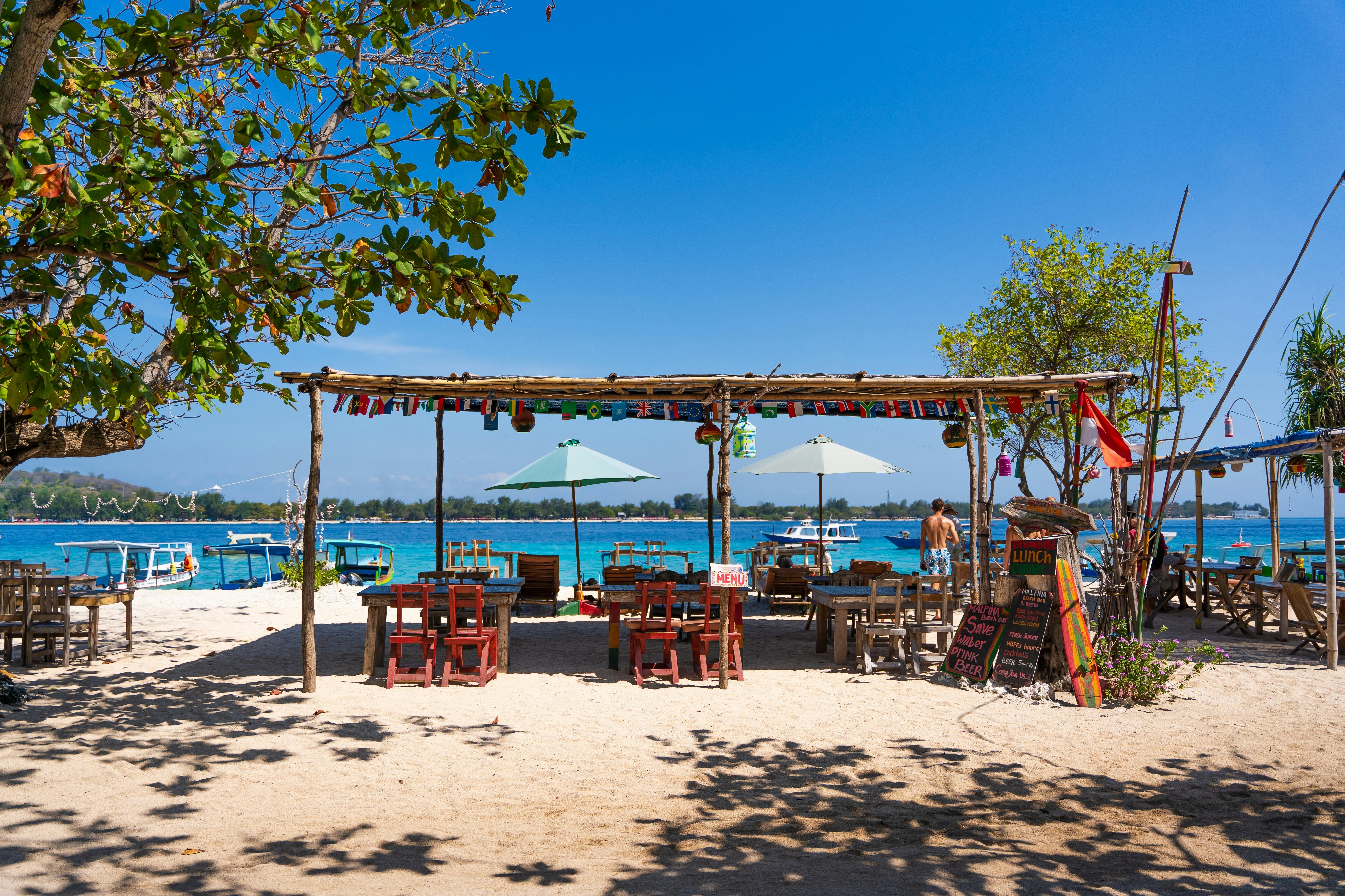 A person seen from the back standing at a beach bar on Gili Meno