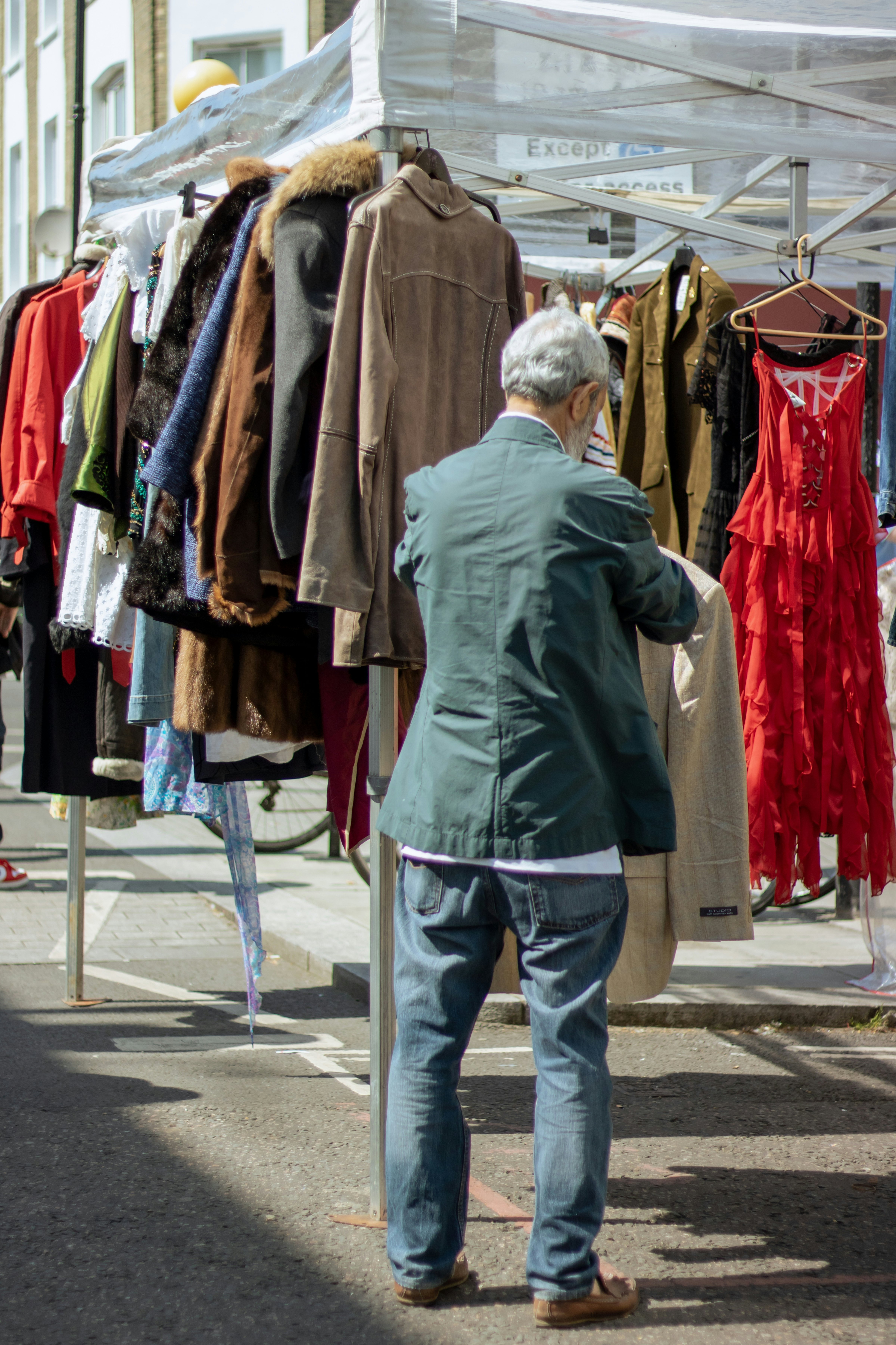 Vintage clothes stand at Portobello Market with a man checking some clothes. London