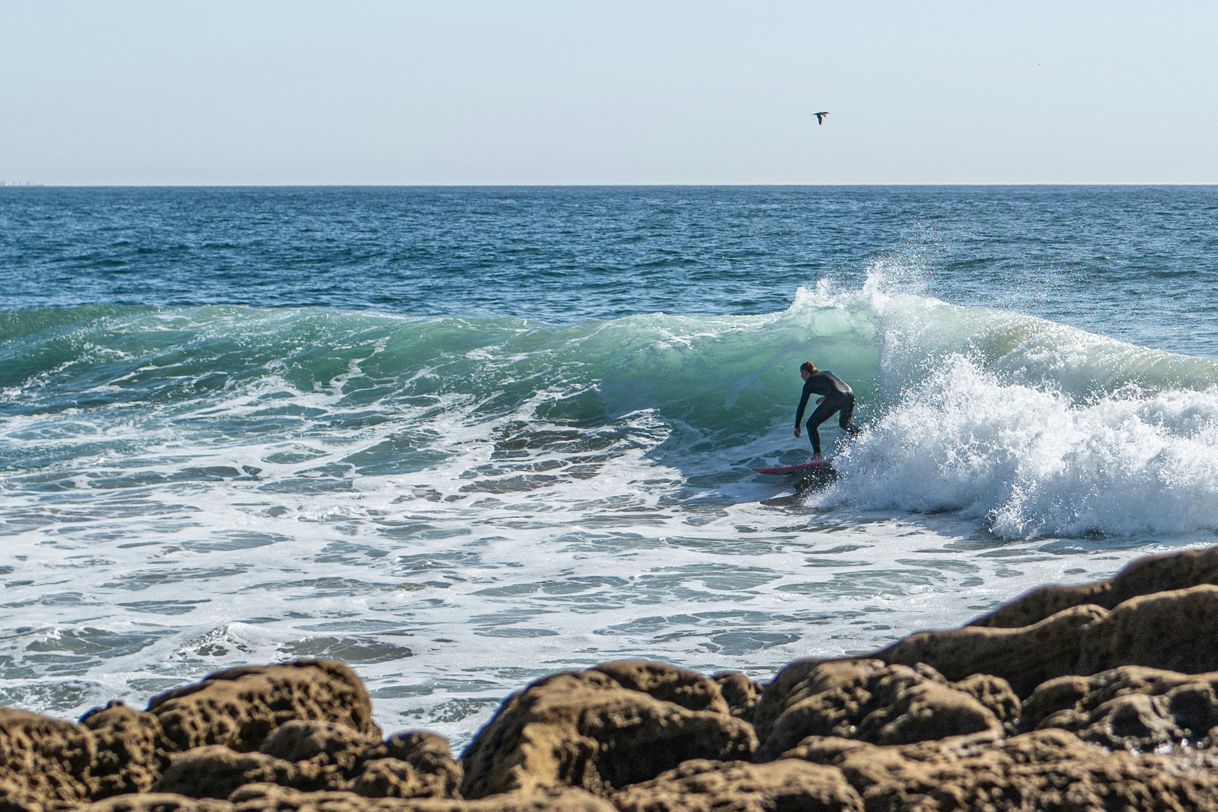 A lone surfer by rocks