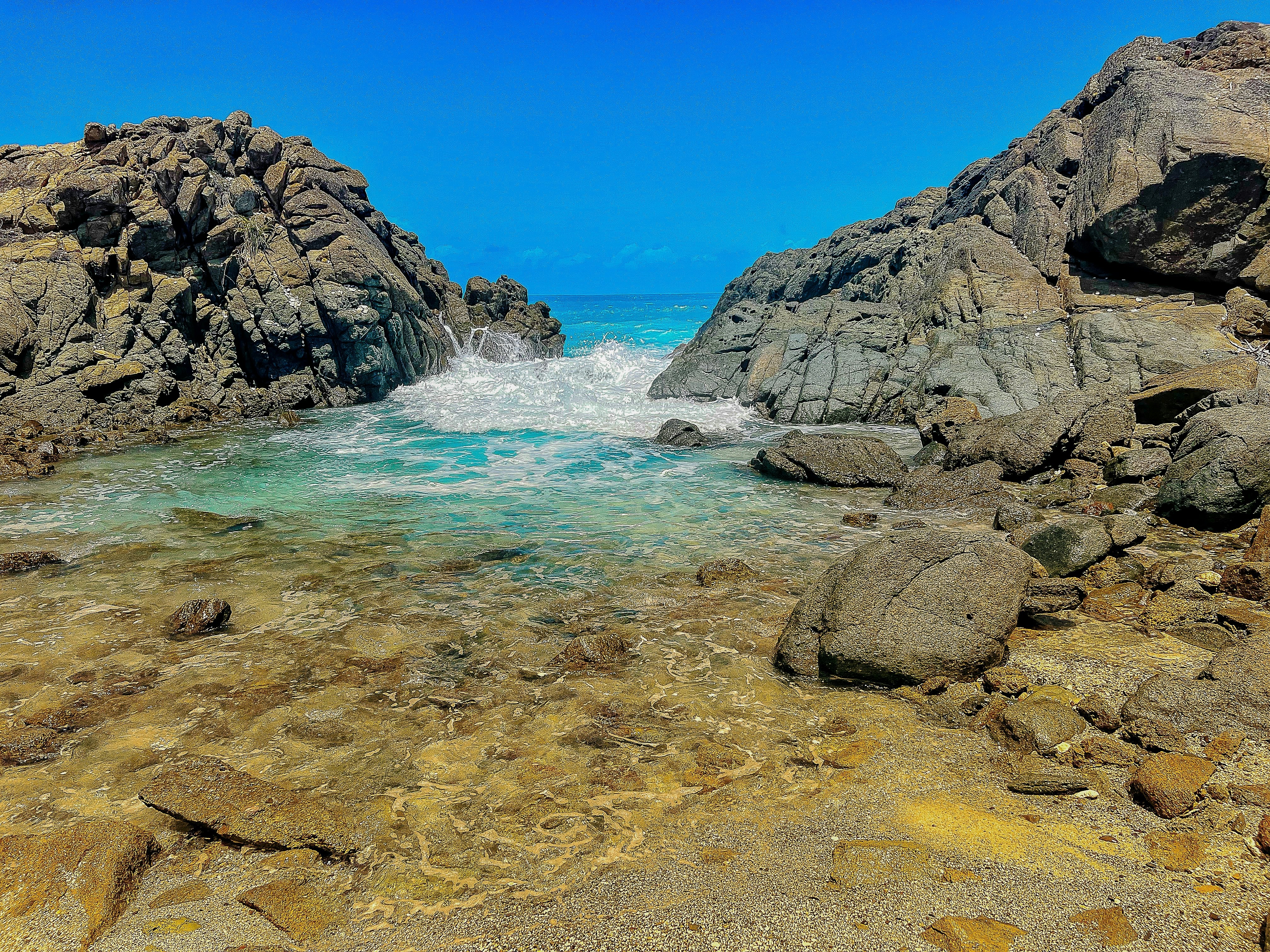 Waves crash in a rocky inlet on a tropical island.