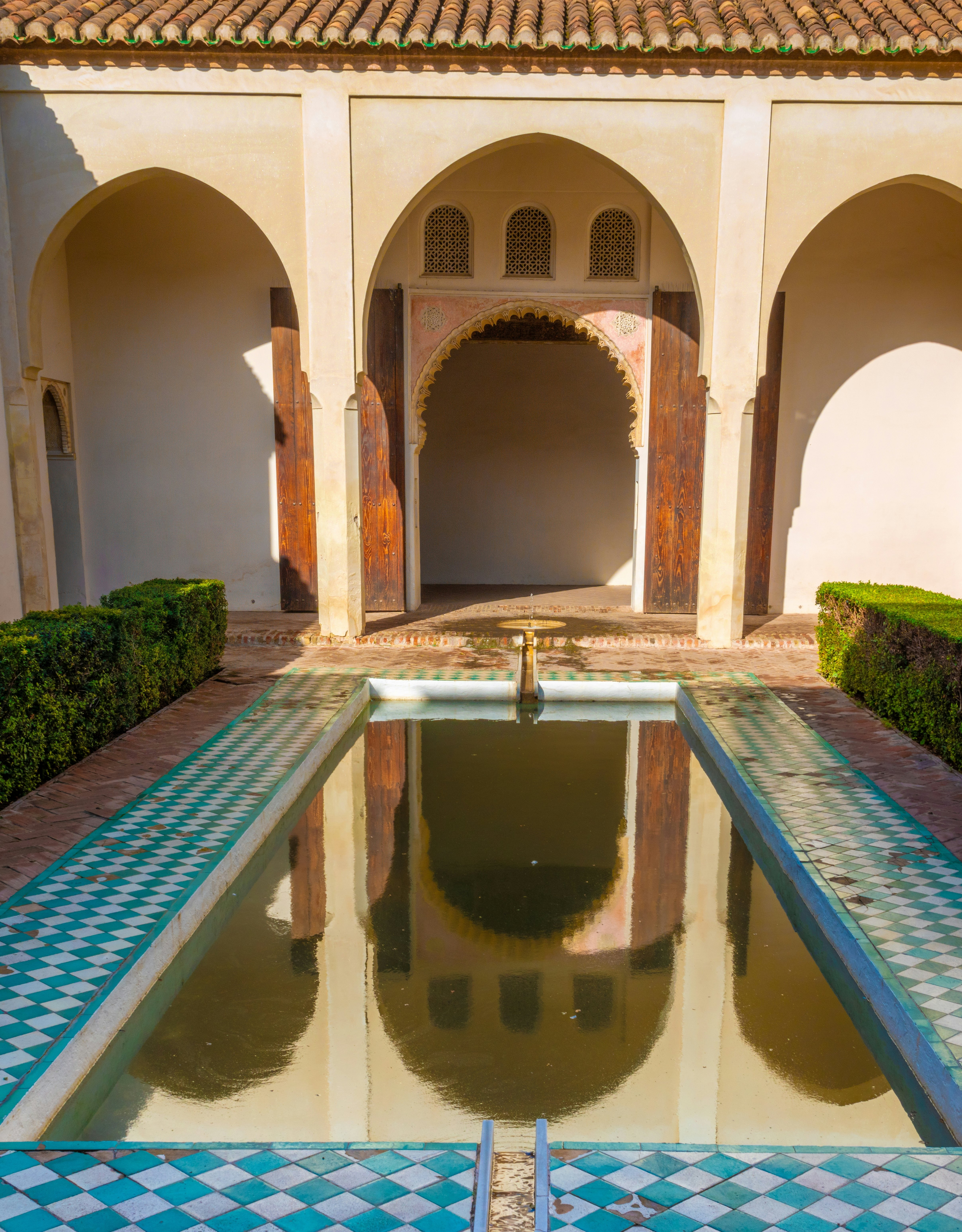 The arches of a doorway and pillars reflect in a small rectangular pool