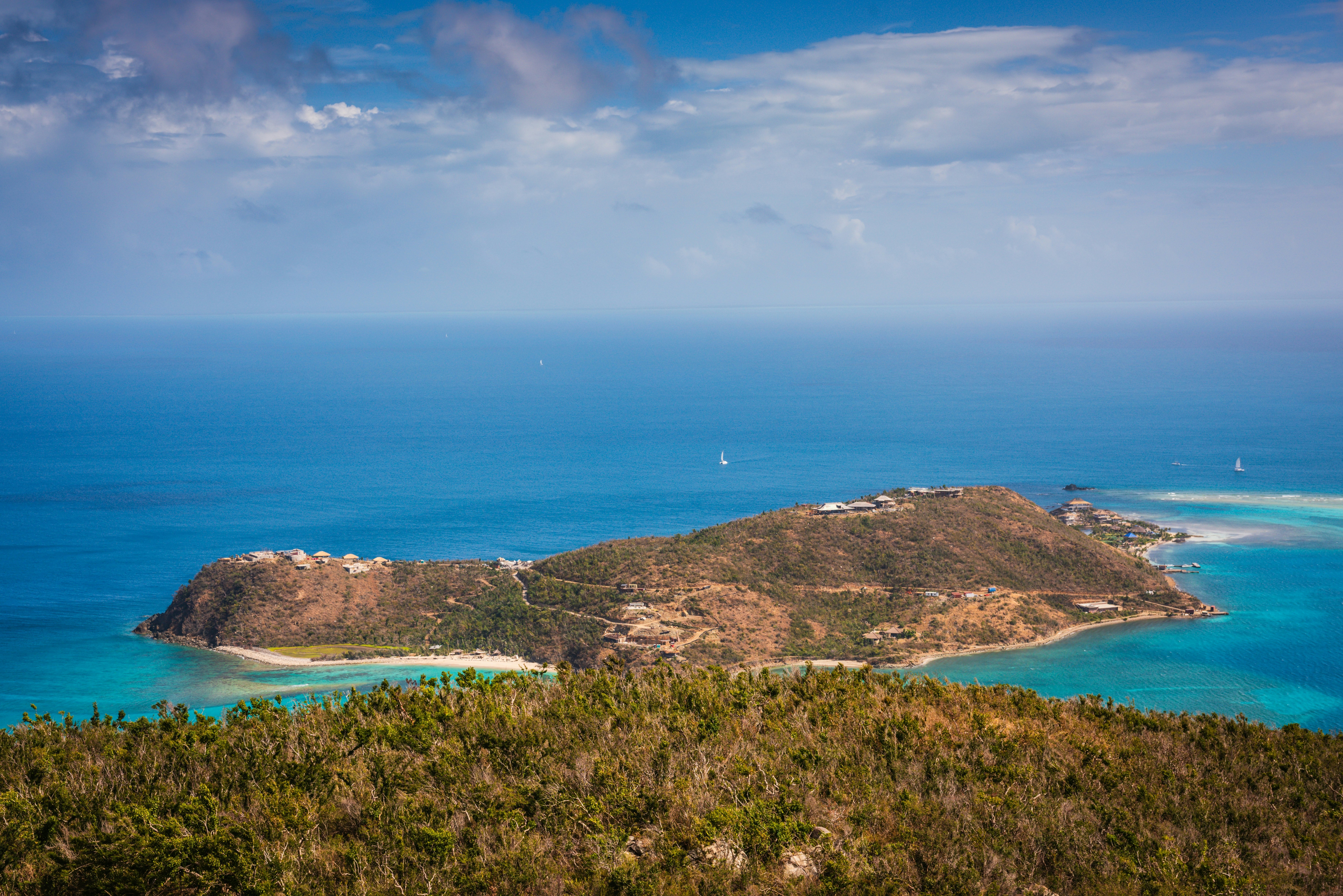 The view of a dry forest and the ocean beyond on a tropical island.