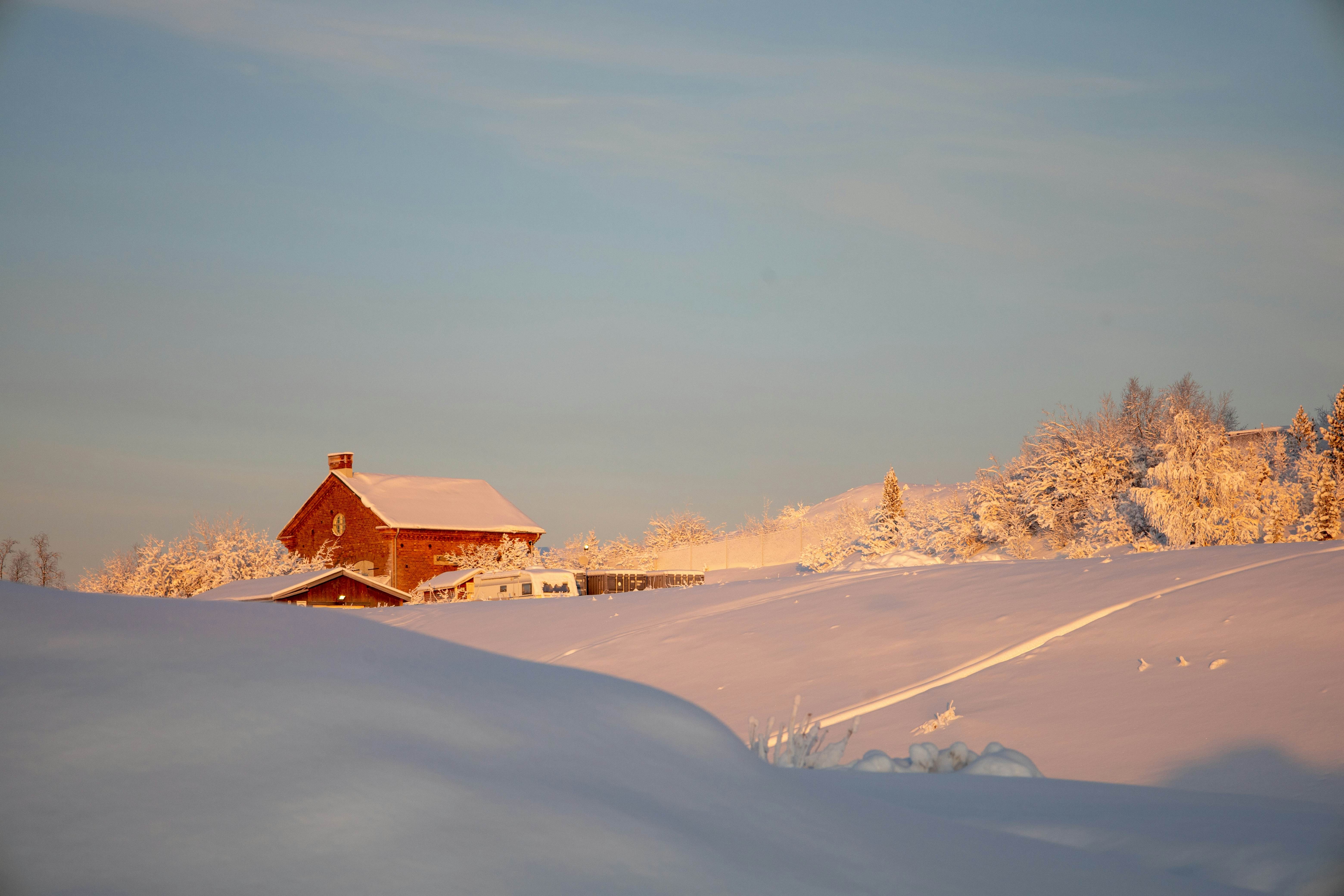 Red building with snow on roof amidst a snowy scene under a cold blue sky